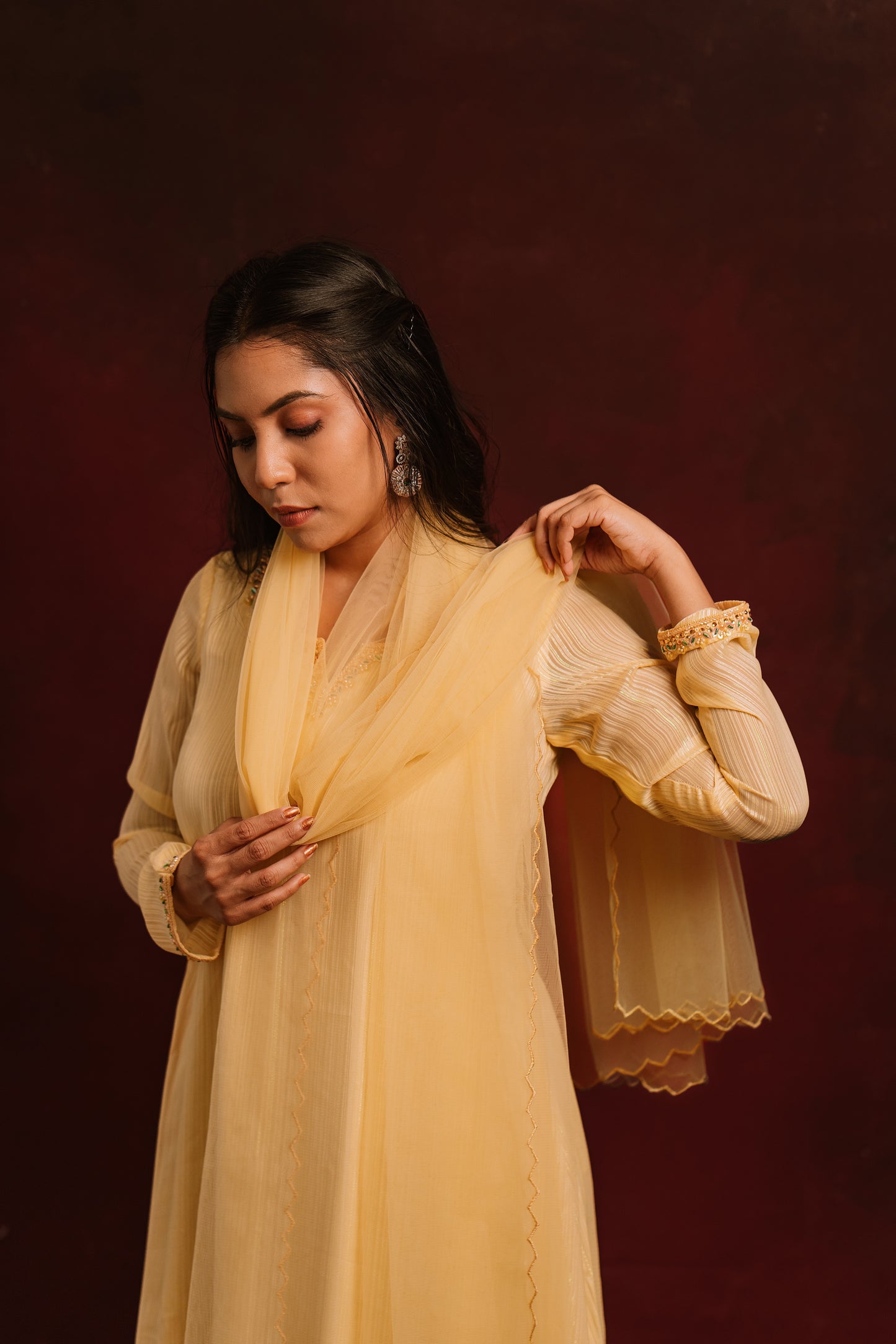 Model Dolly Aishwarya posing for photoshoot in a hand embroidered chiffon salwar set in yellow paired with a tulle dupatta by team AKloset.