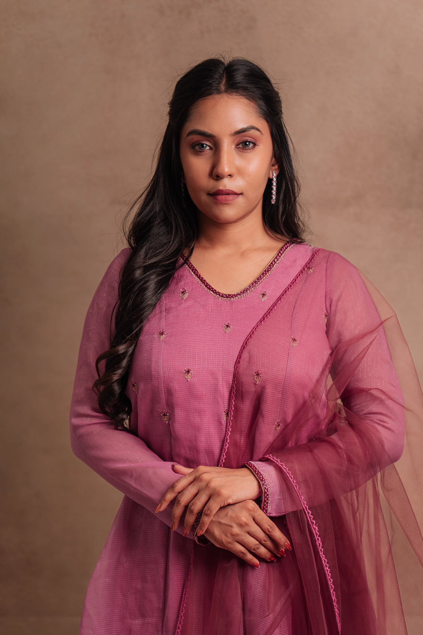 Model Dolly Aishwarya posing for photoshoot in a hand embroidered tissue chiffon salwar set in onion pink paired with a tulle dupatta by team AKloset.