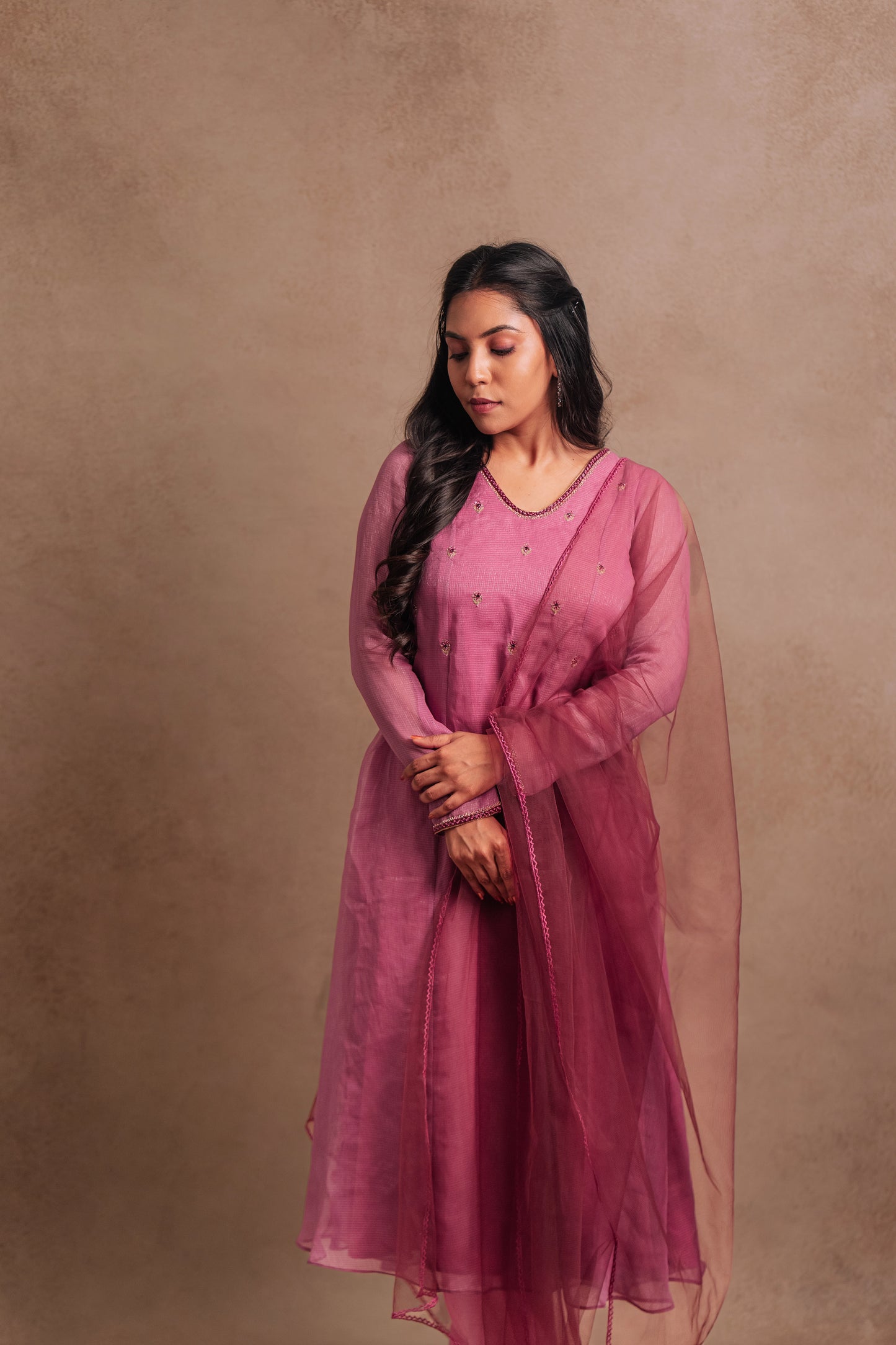 Model Dolly Aishwarya posing in a hand embroidered tissue chiffon salwar set in onion pink paired with a tulle dupatta by team AKloset.