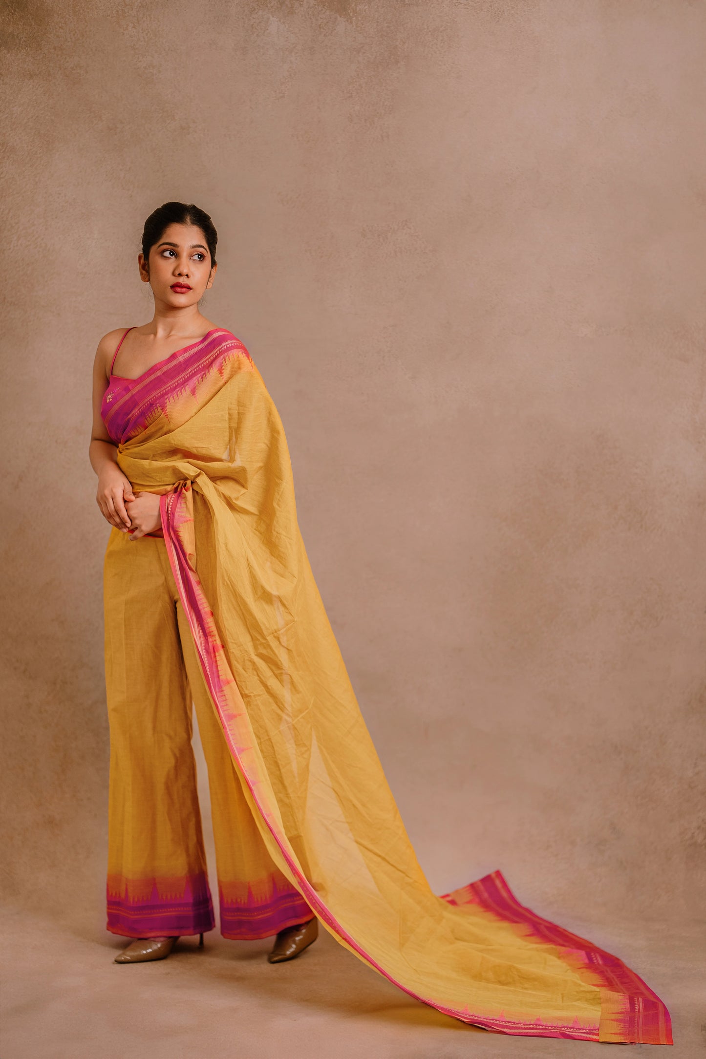 Model Jaina Parmar in a draped pant saree in yellow paired with a hot pink spaghetti strap blouse by team AKloset.