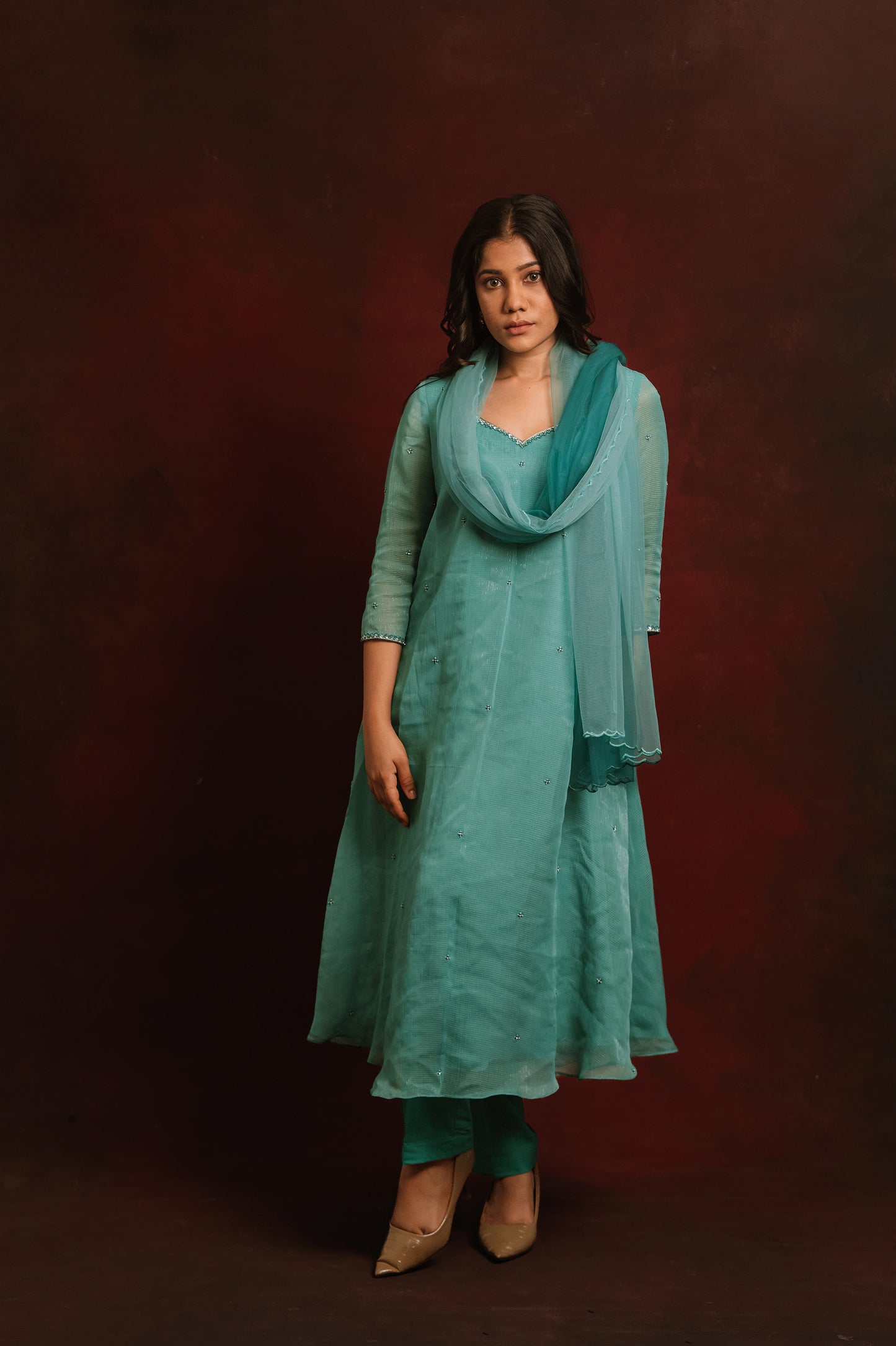 Model Jaina Parmar posing for front profile in a salwar set in shades of teal and turquoise tissue chiffon paired with a tulle ombre dupatta by team AKloset.