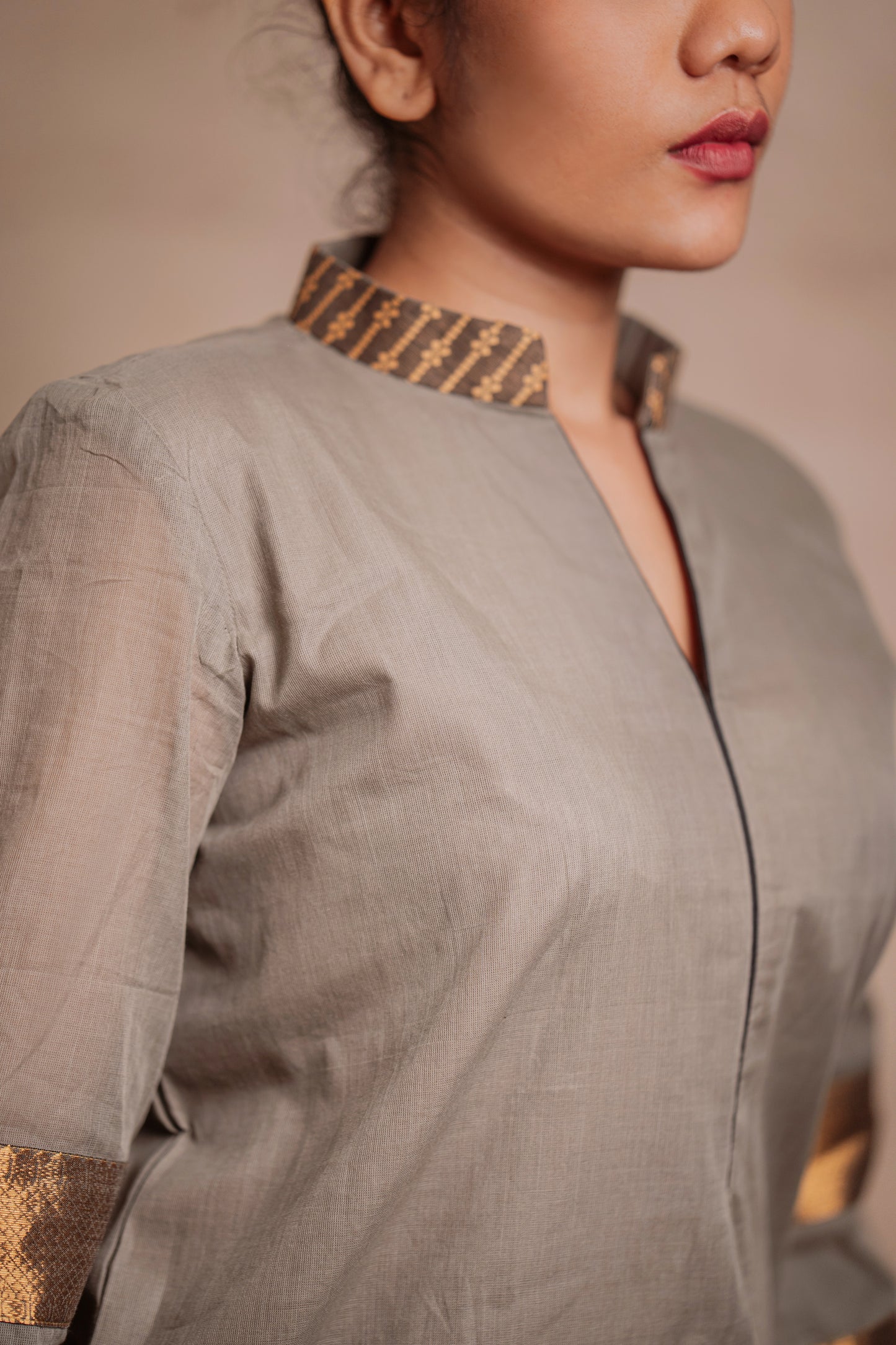 Model Jaina Parmar posing for neckline detailing in an oversized kurti in gray with bell sleeves paired with a black pant by team AKloset.