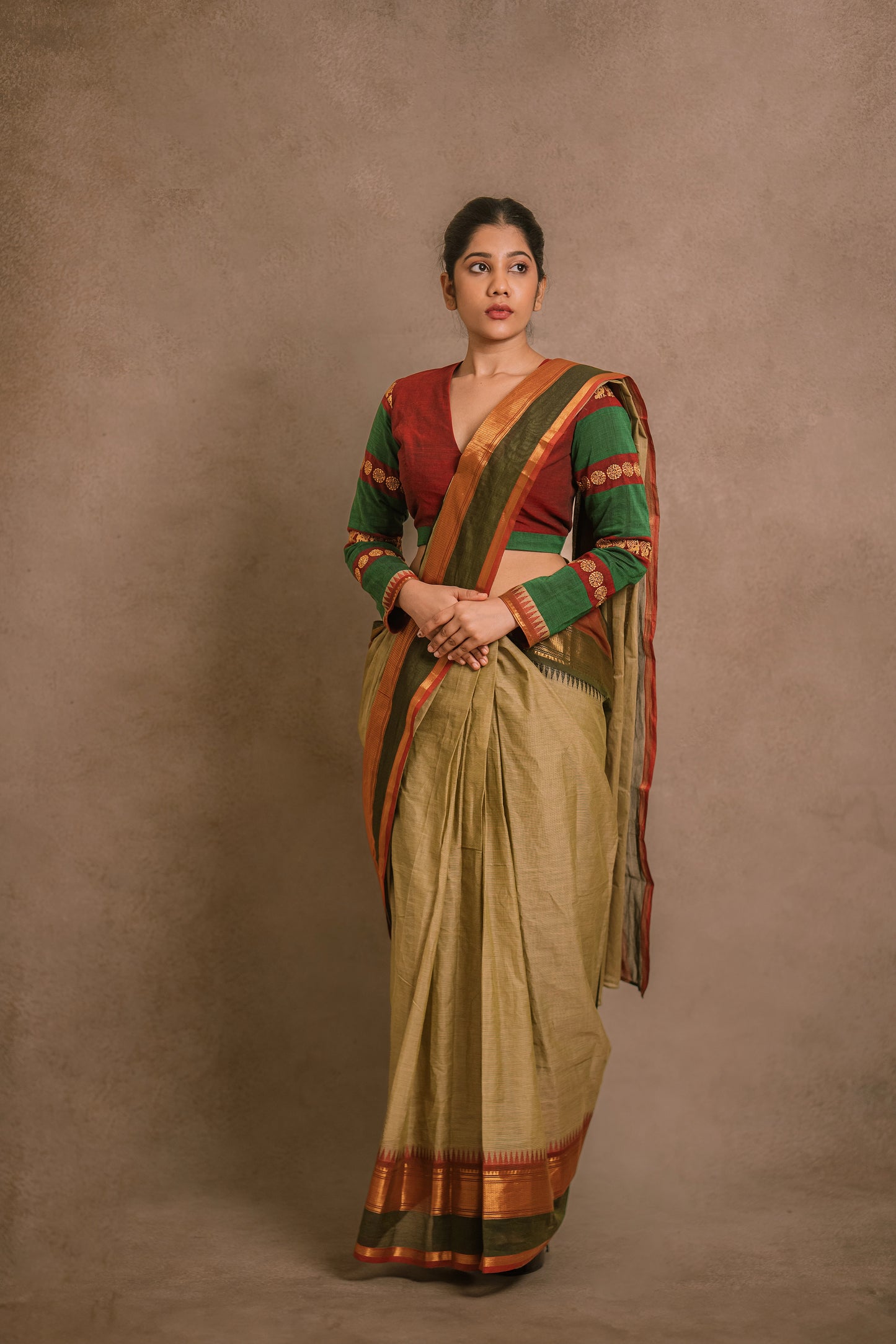 Model Jaina Parmar posing for photoshoot in a draped saree in sage green with a hand embroidered blouse in maroon & green by team AKloset.