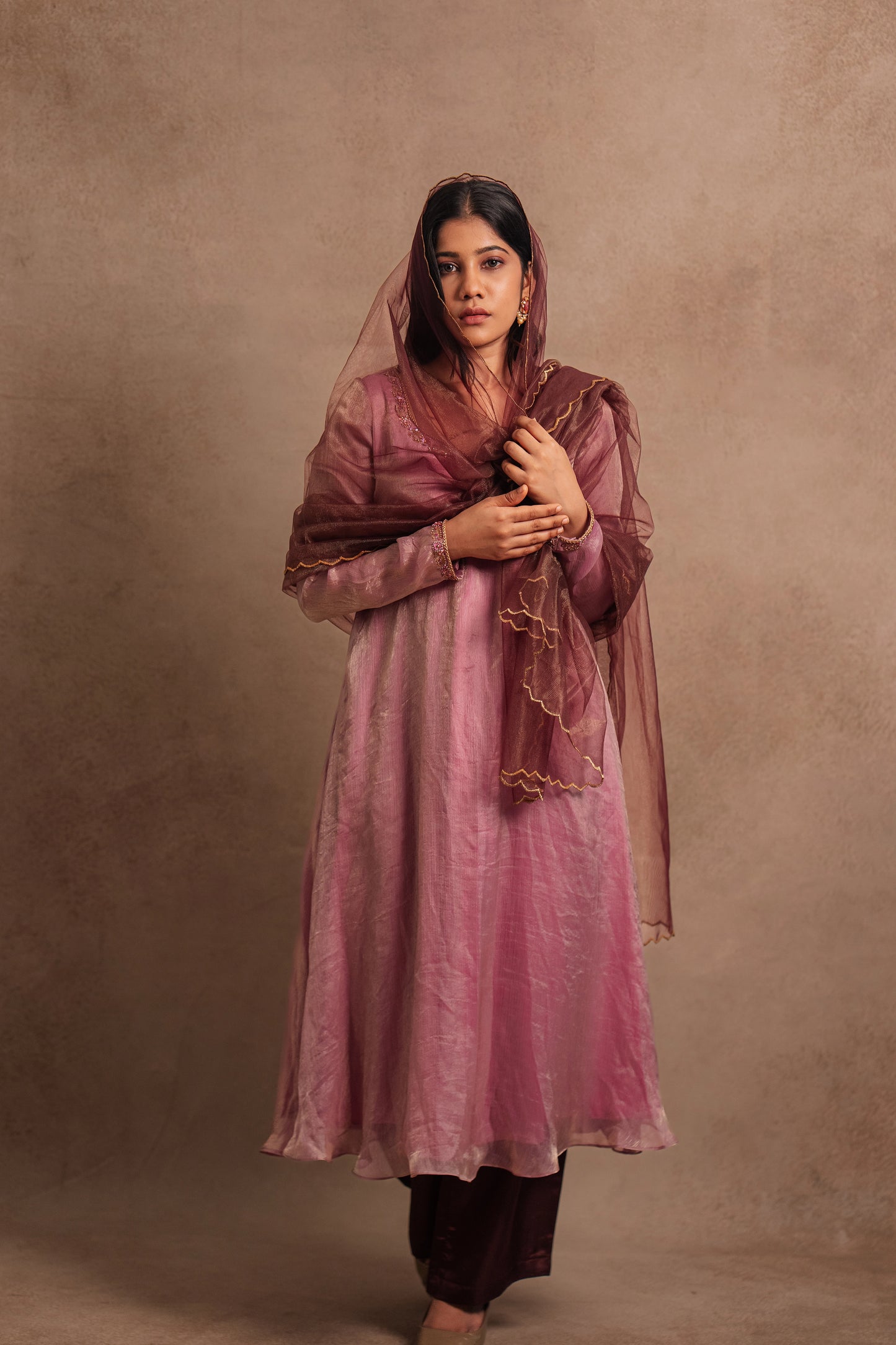 Model Jaina Parmar posing for photoshoot in a hand embroidered tissue chiffon anarkali in onion pink (dual tone), paired with an embroidered tulle dupatta in wine red by team AKloset.