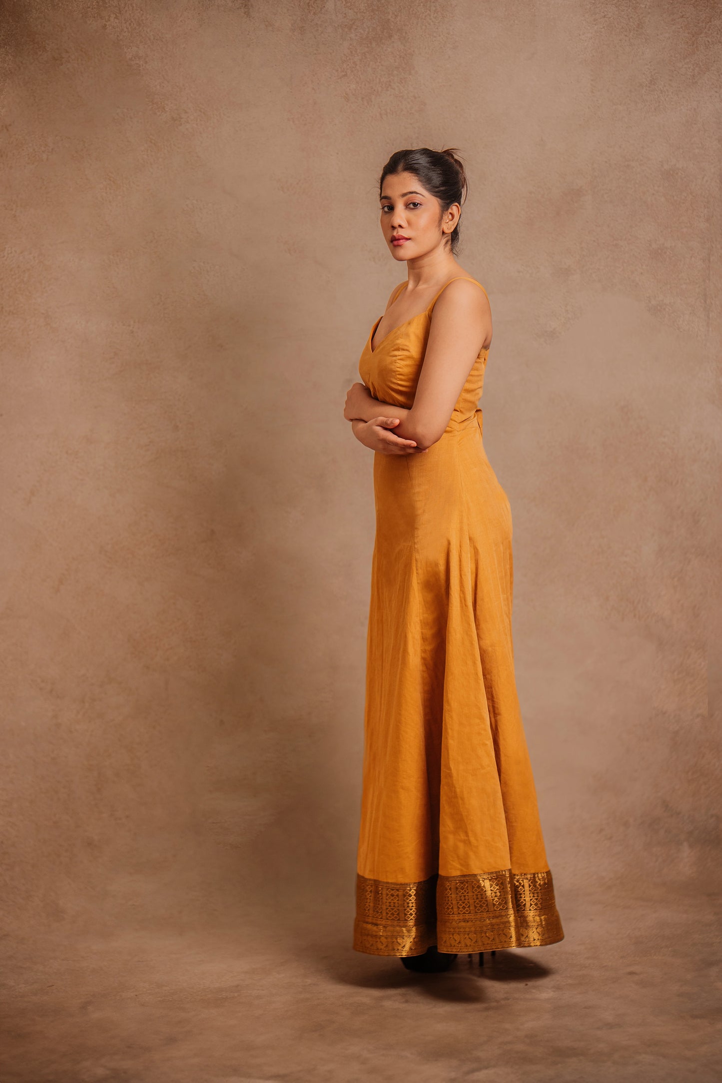 Model Jaina Parmar posing for side profile in a corset dress in mustard by team AKloset.