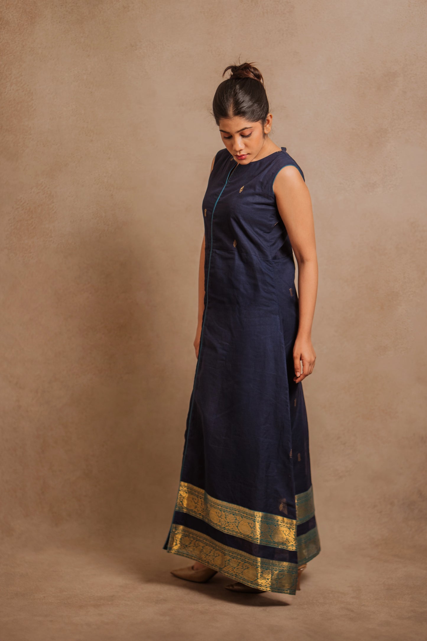 Model Jaina Parmar posing for side profile in a sleeveless a-line dress in blue by team AKloset.