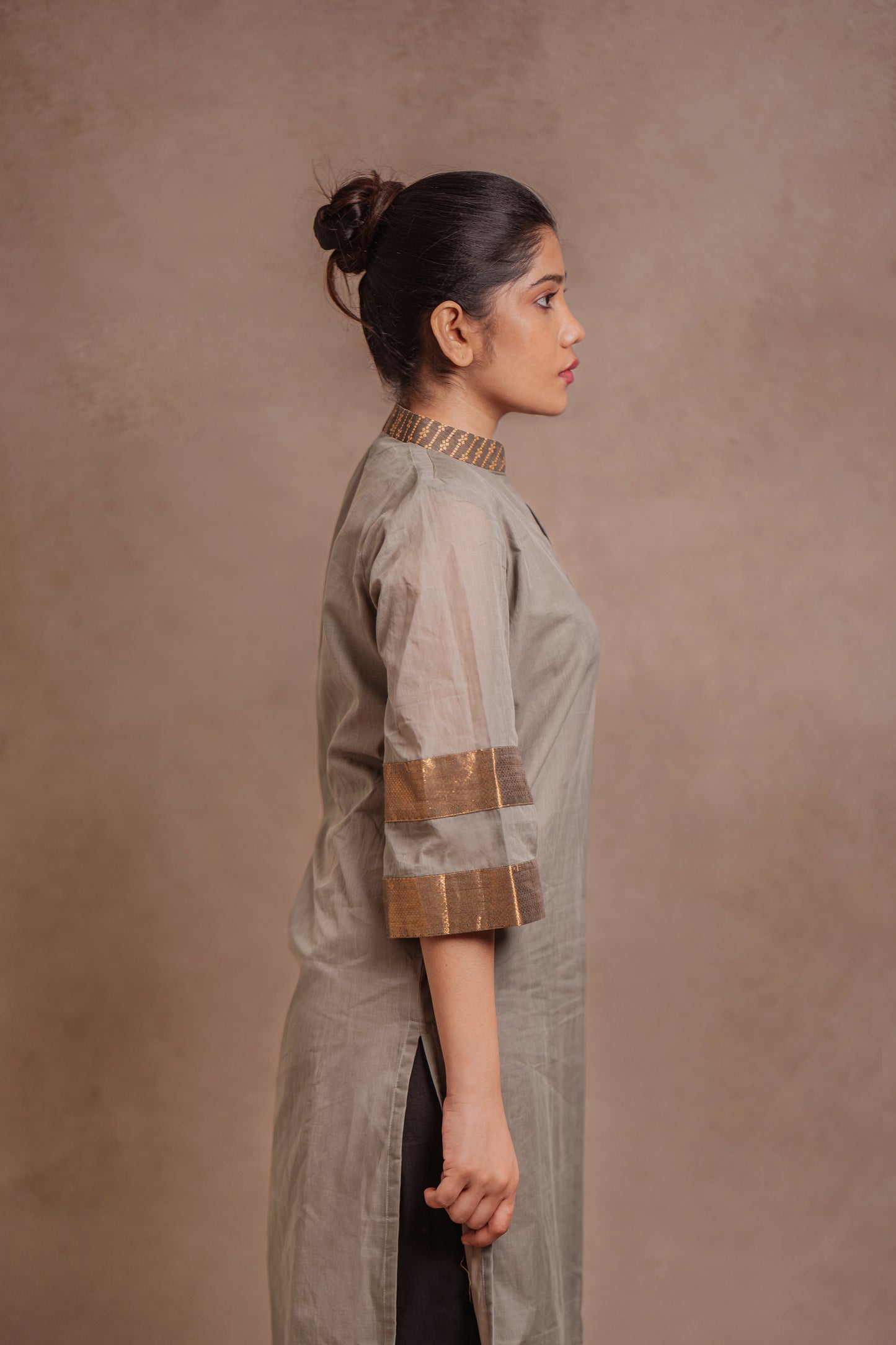 Model Jaina Parmar posing for side profile in an oversized kurti in gray with bell sleeves paired with a black pant by team AKloset.