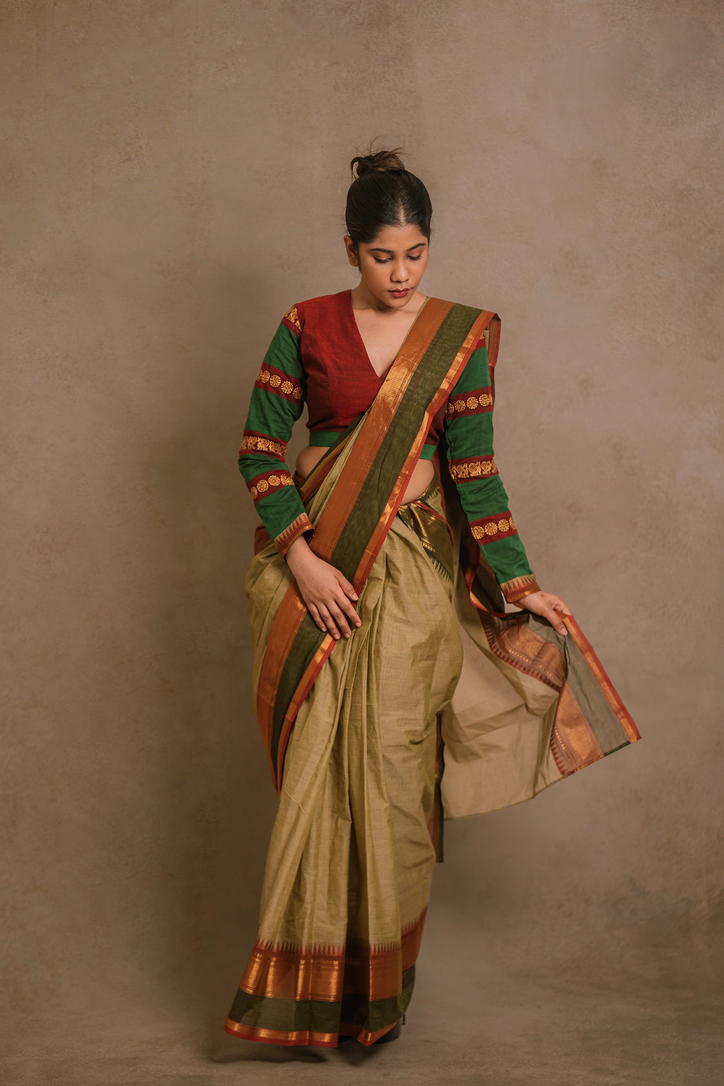 Model Jaina Parmar posing in a draped saree in sage green with a hand embroidered blouse in maroon & green by team AKloset.