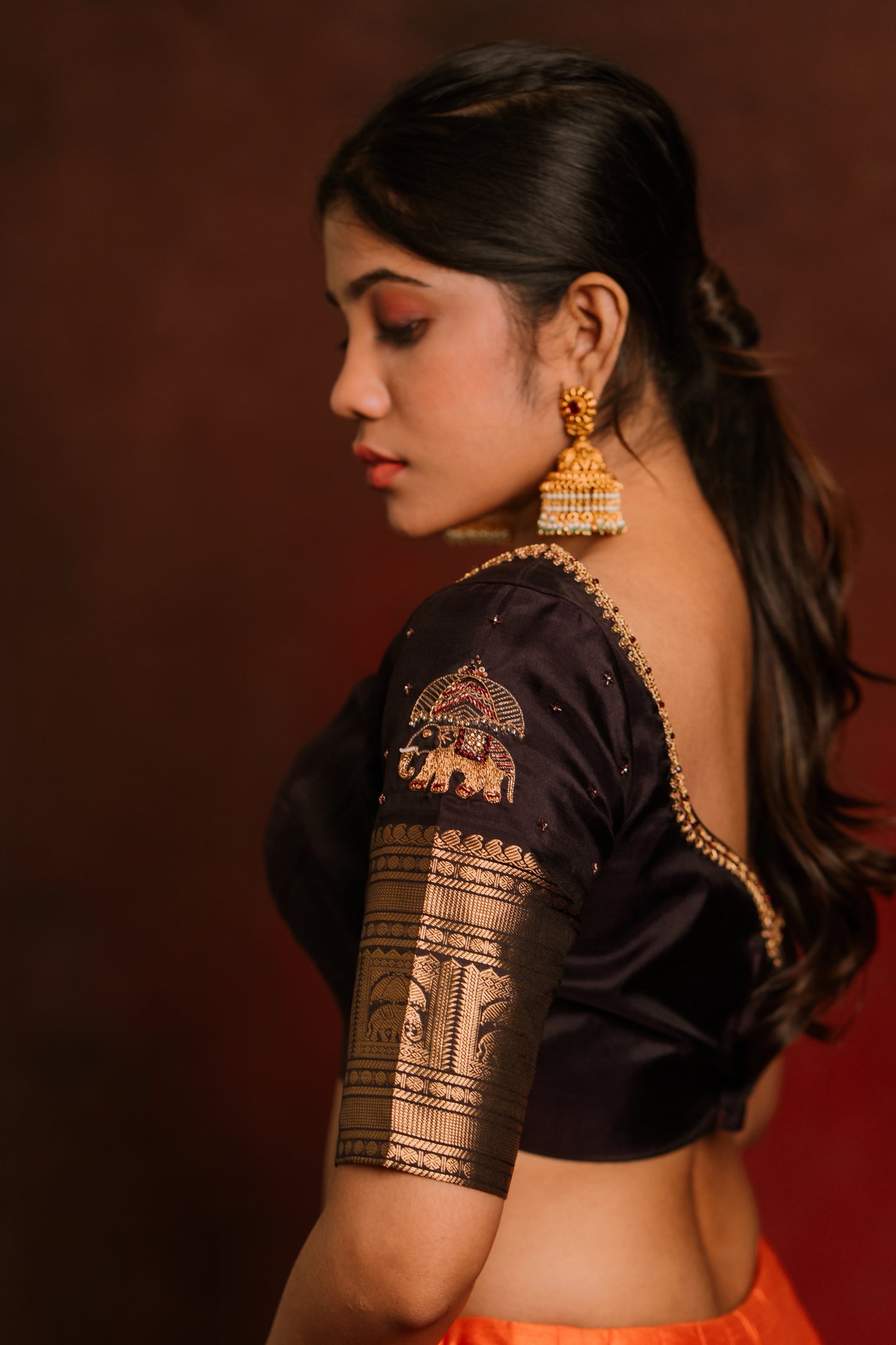 Model Jaina Parmar posing in a hand embroidered kanjivaram silk blouse in brown by team AKloset. Fashionable, high-quality craftsmanship that is stylish and affordable.