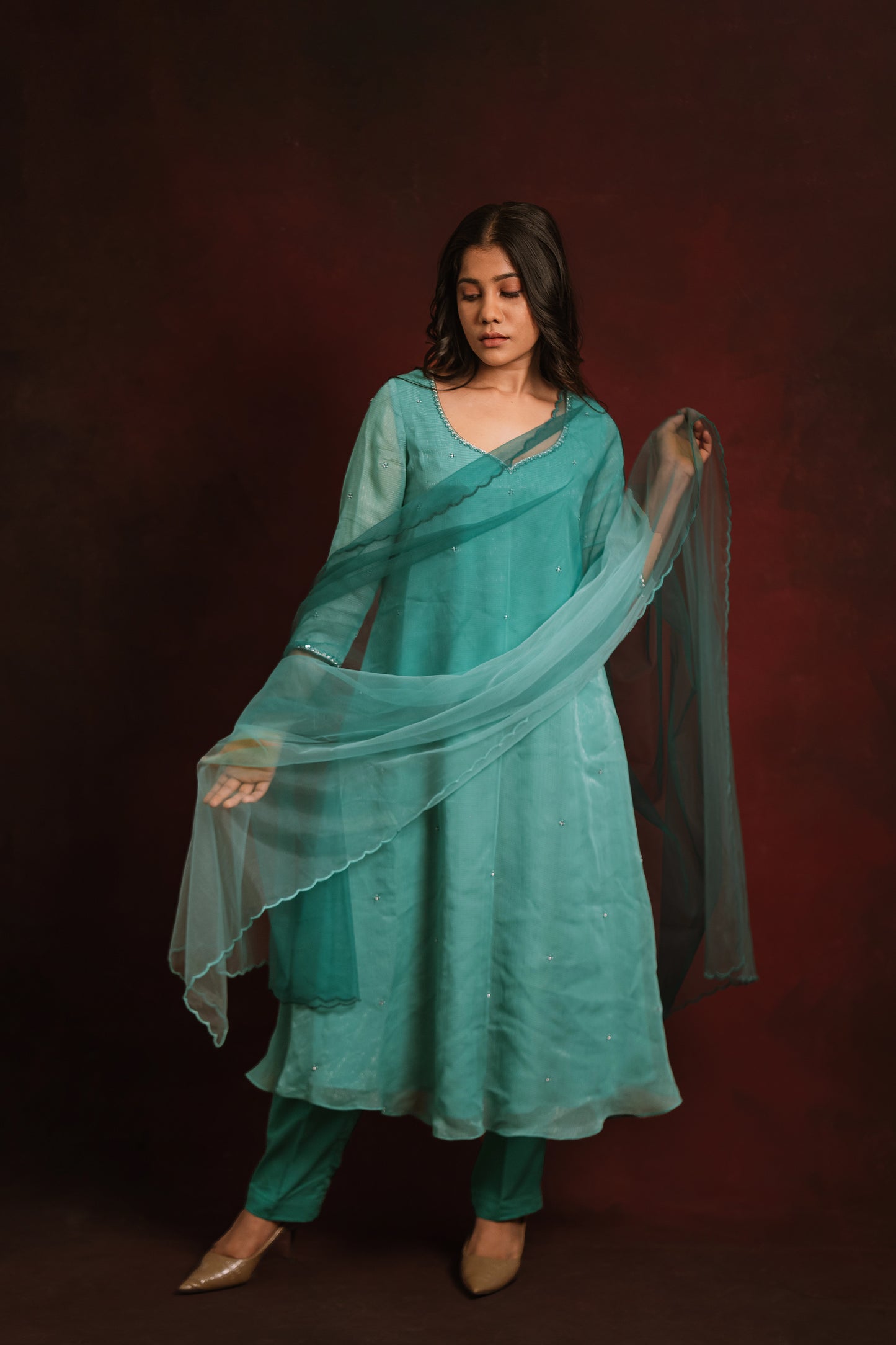 Model Jaina Parmar posing in a salwar set in shades of teal and turquoise tissue chiffon paired with a tulle ombre dupatta by team AKloset.