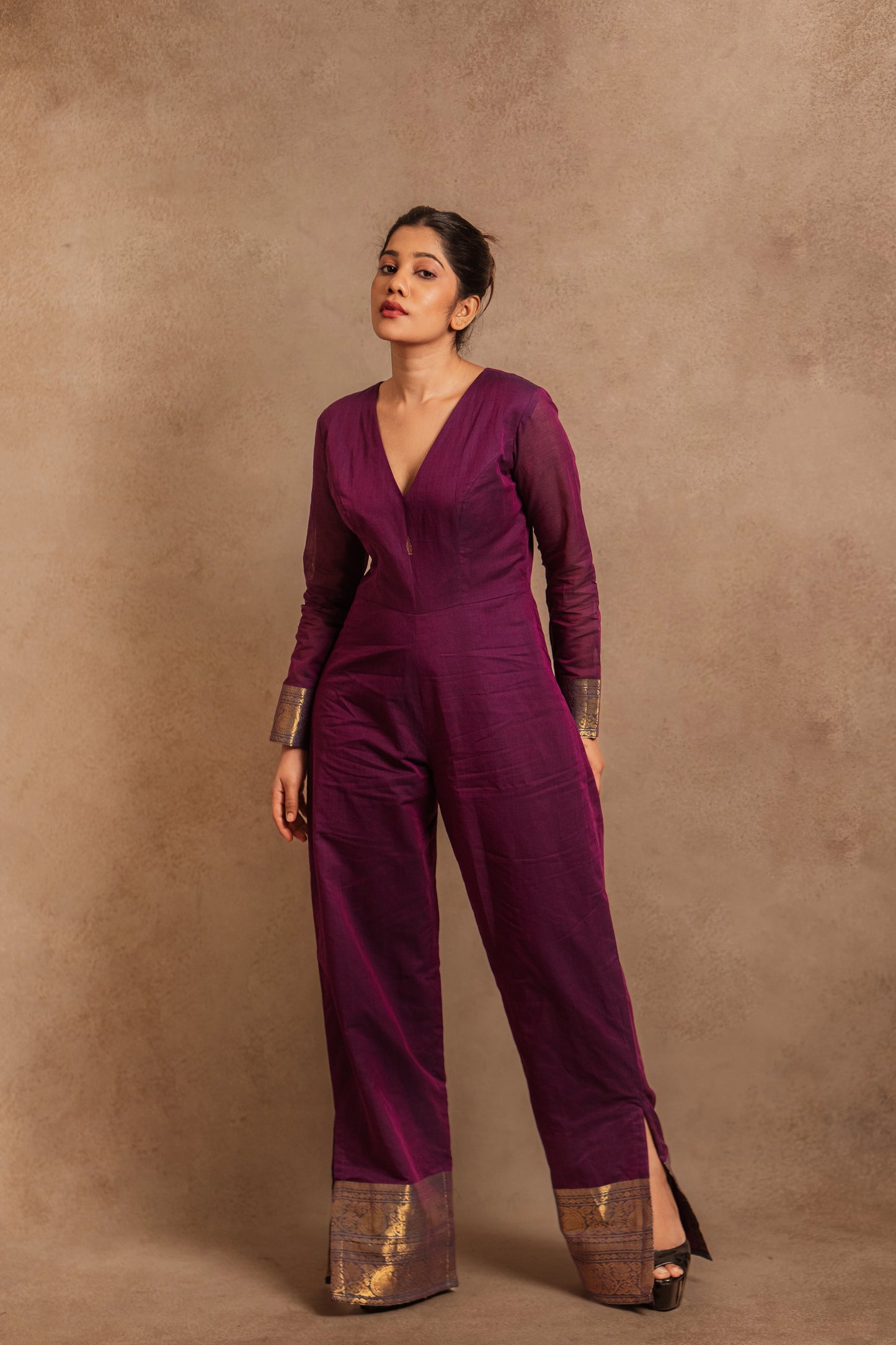 Model Jaina Parmar posing in a v-neck purple jumpsuit with a stylish low slit by team AKloset.