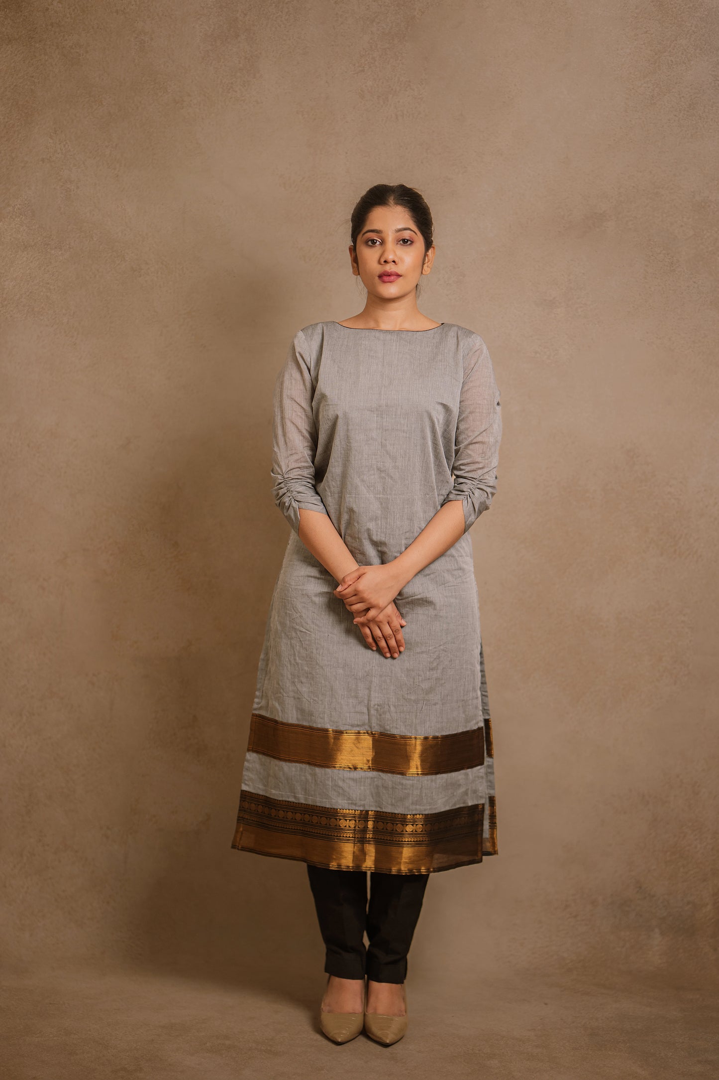 Model Jaina Parmar posing in an oversized gray kurti by team AKloset. A South Edit (Kanjivaram) piece is differentiated by the extravagant border native to Kanjivaram.