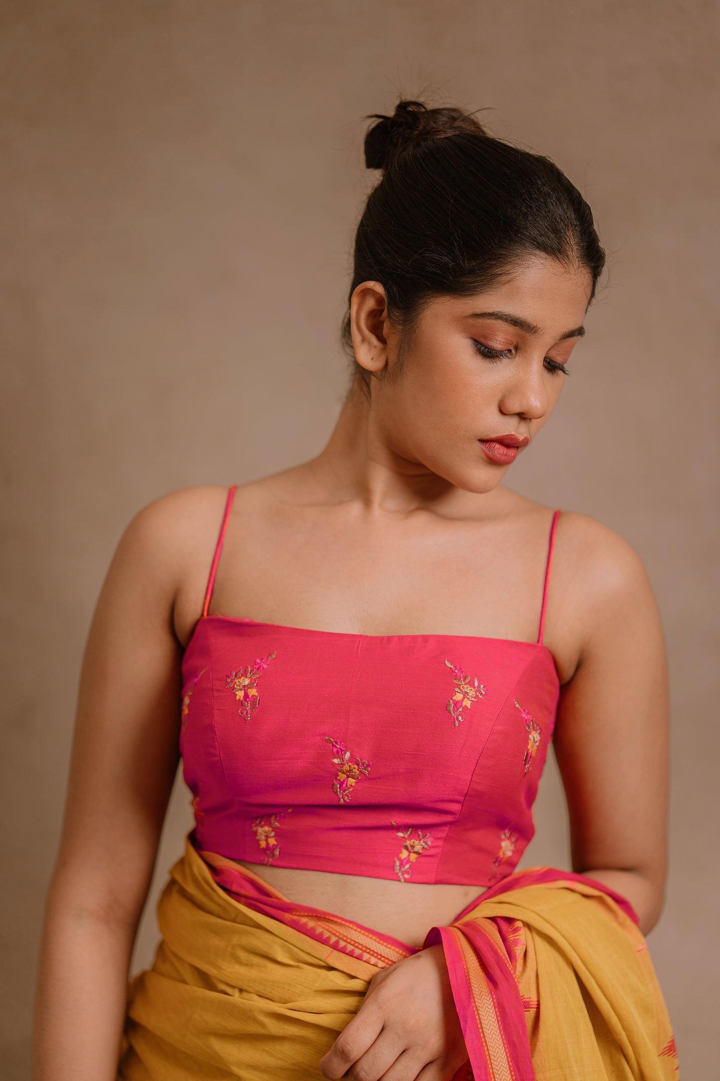 Model Jaina Parmar showcasing blouse detailing in a draped pant saree in yellow paired with a hot pink spaghetti strap blouse by team AKloset.
