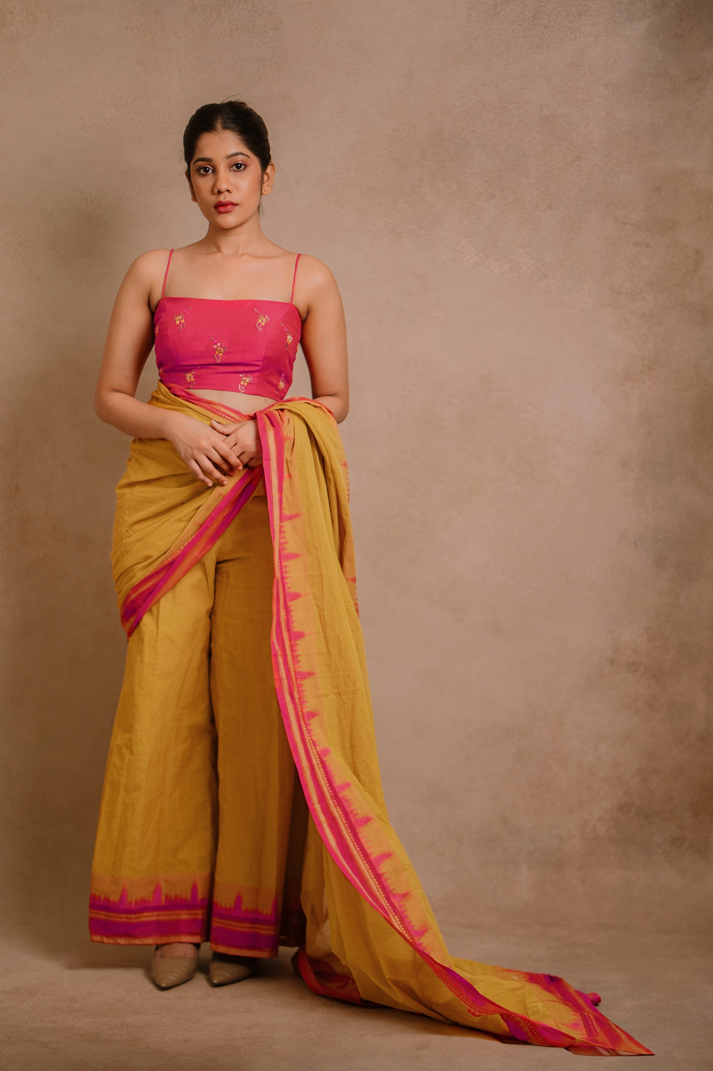 Model Jaina Parmar showcasing blouse look in a draped pant saree in yellow paired with a hot pink spaghetti strap blouse by team AKloset.