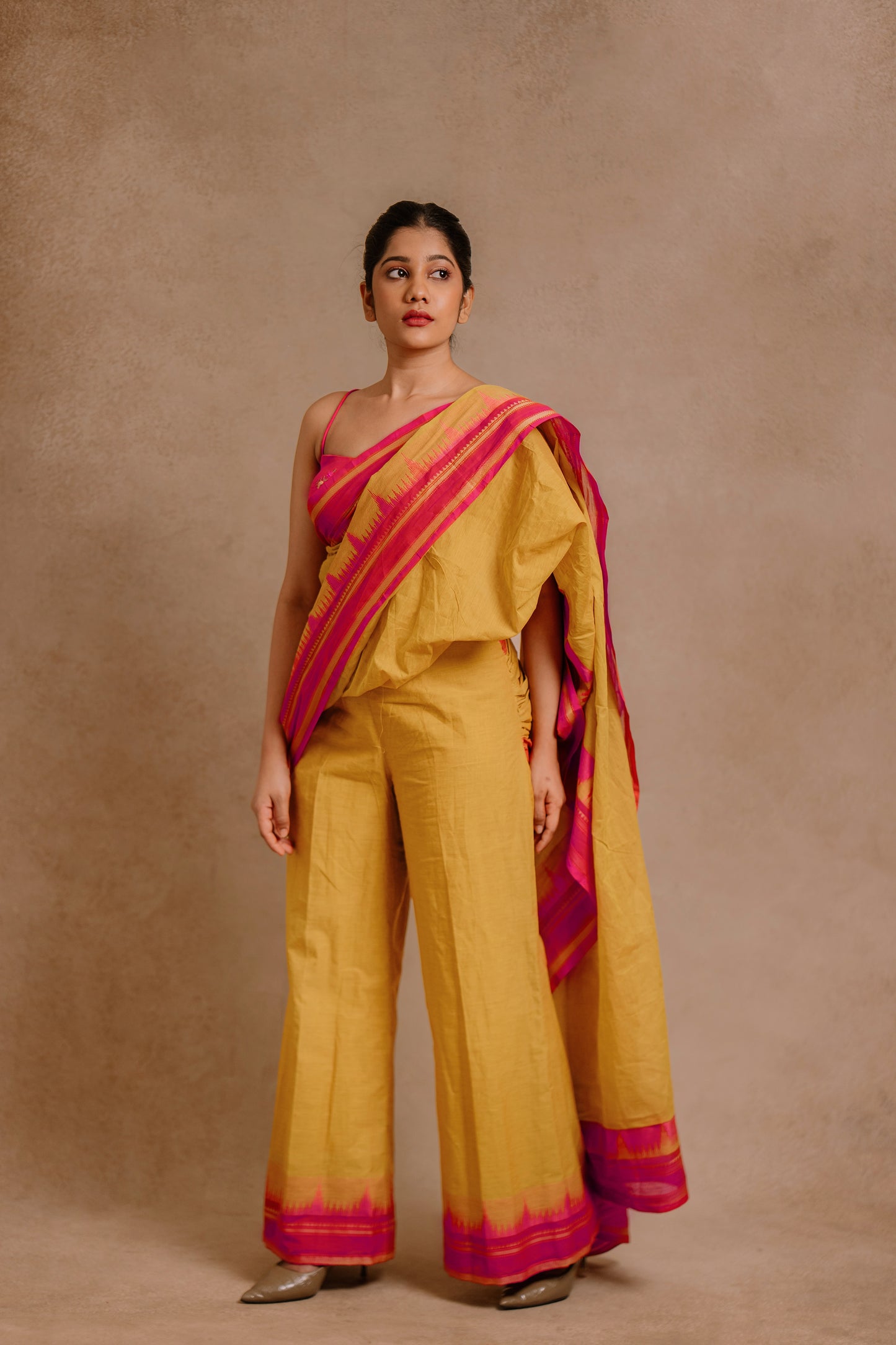 Model Jaina Parmar showcasing drapes in a draped pant saree in yellow paired with a hot pink spaghetti strap blouse by team AKloset.