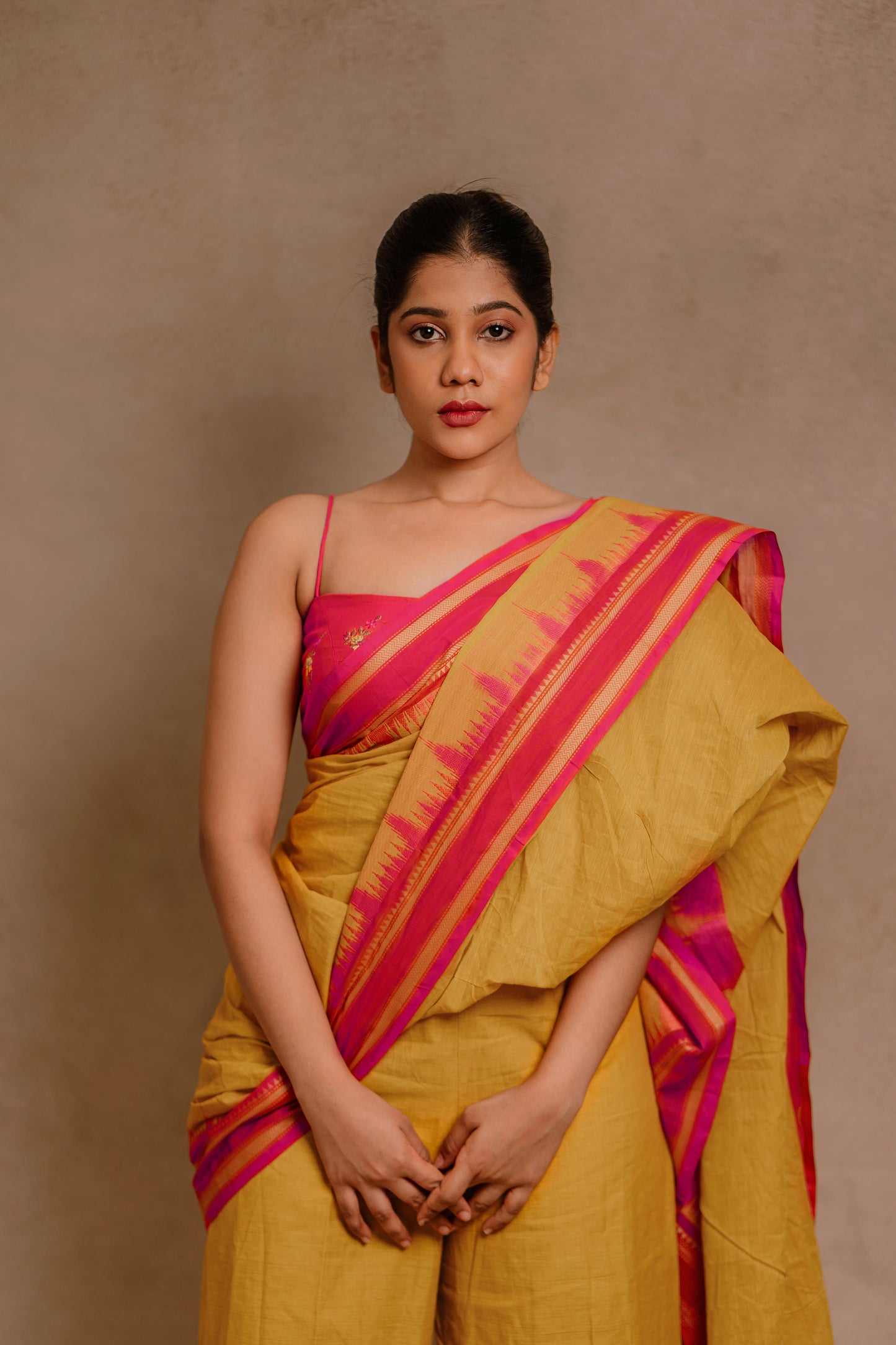 Model Jaina Parmar showcasing front profile in a draped pant saree in yellow paired with a hot pink spaghetti strap blouse by team AKloset.