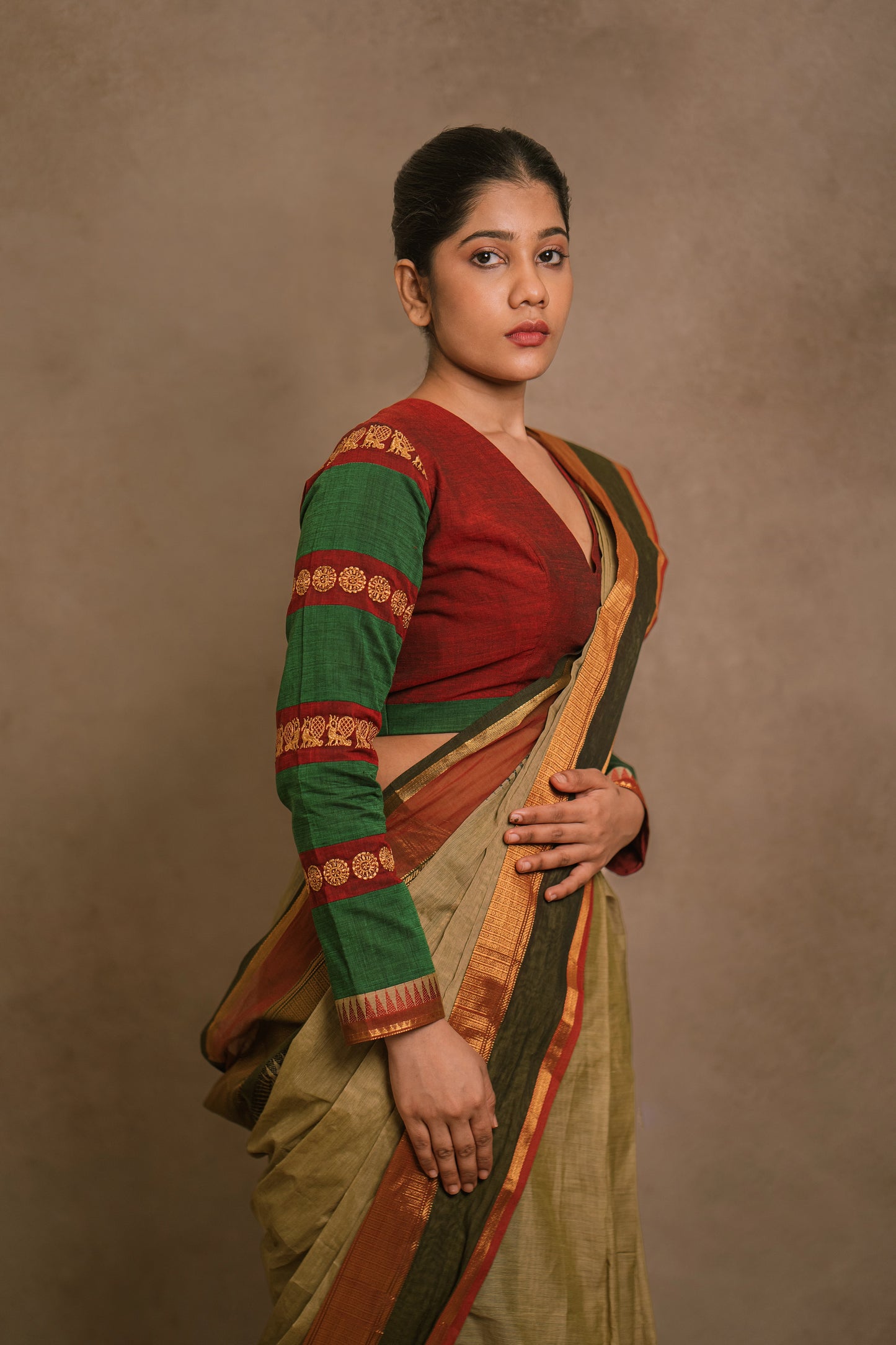 Model Jaina Parmar showcasing side profile in a draped saree in sage green with a hand embroidered blouse in maroon & green by team AKloset.