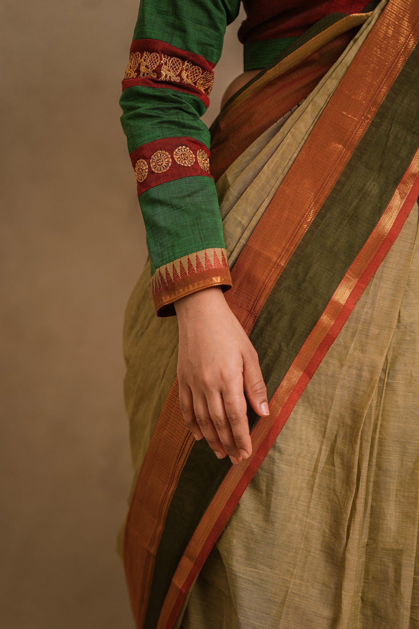 Model Jaina Parmar showcasing sleeve detailing in a draped saree in sage green with a hand embroidered blouse in maroon & green by team AKloset.