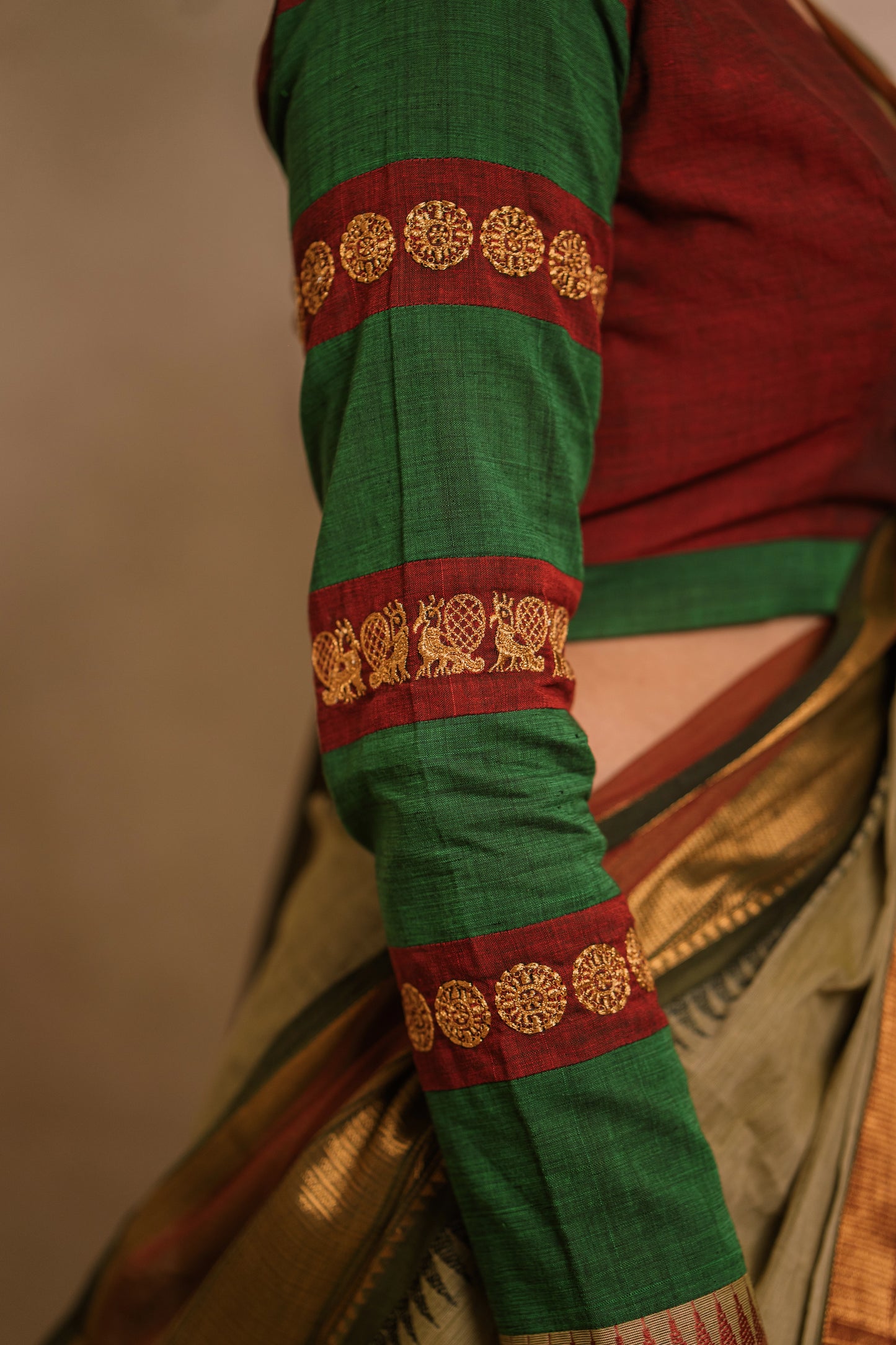 Model Jaina Parmar showcasing sleeve motifs in a draped saree in sage green with a hand embroidered blouse in maroon & green by team AKloset.