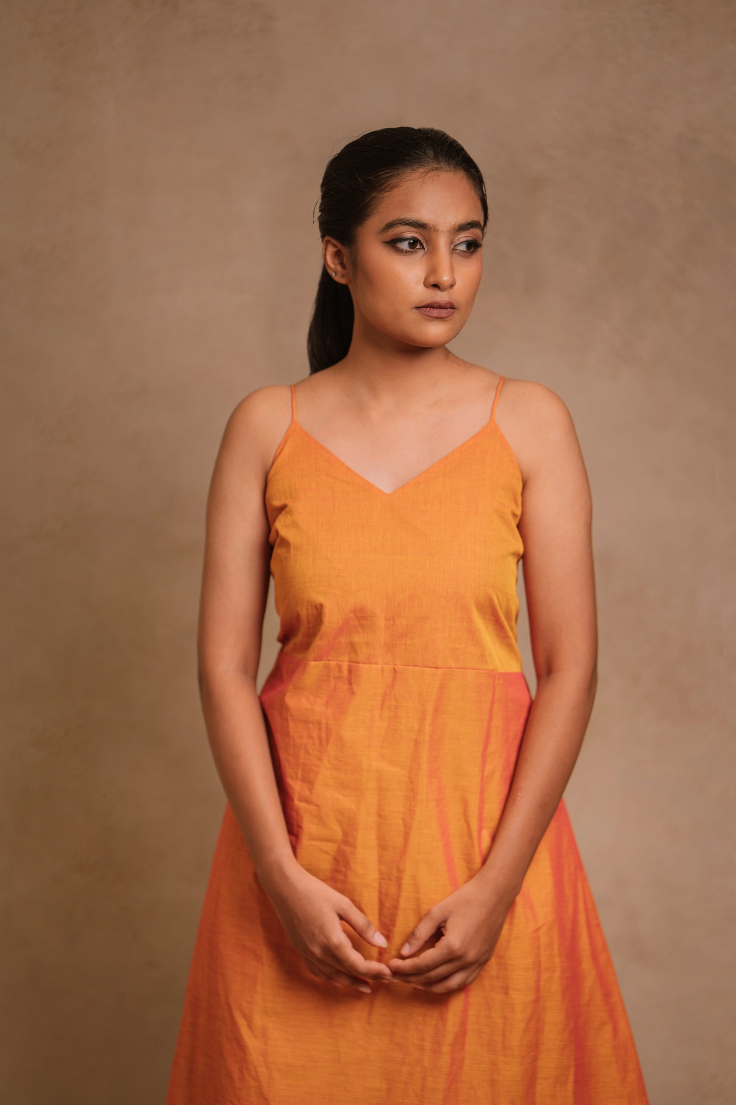 Model Krisha for a photoshoot of an A-line sleeveless dress in orange (dual tone fabric) by team AKloset.