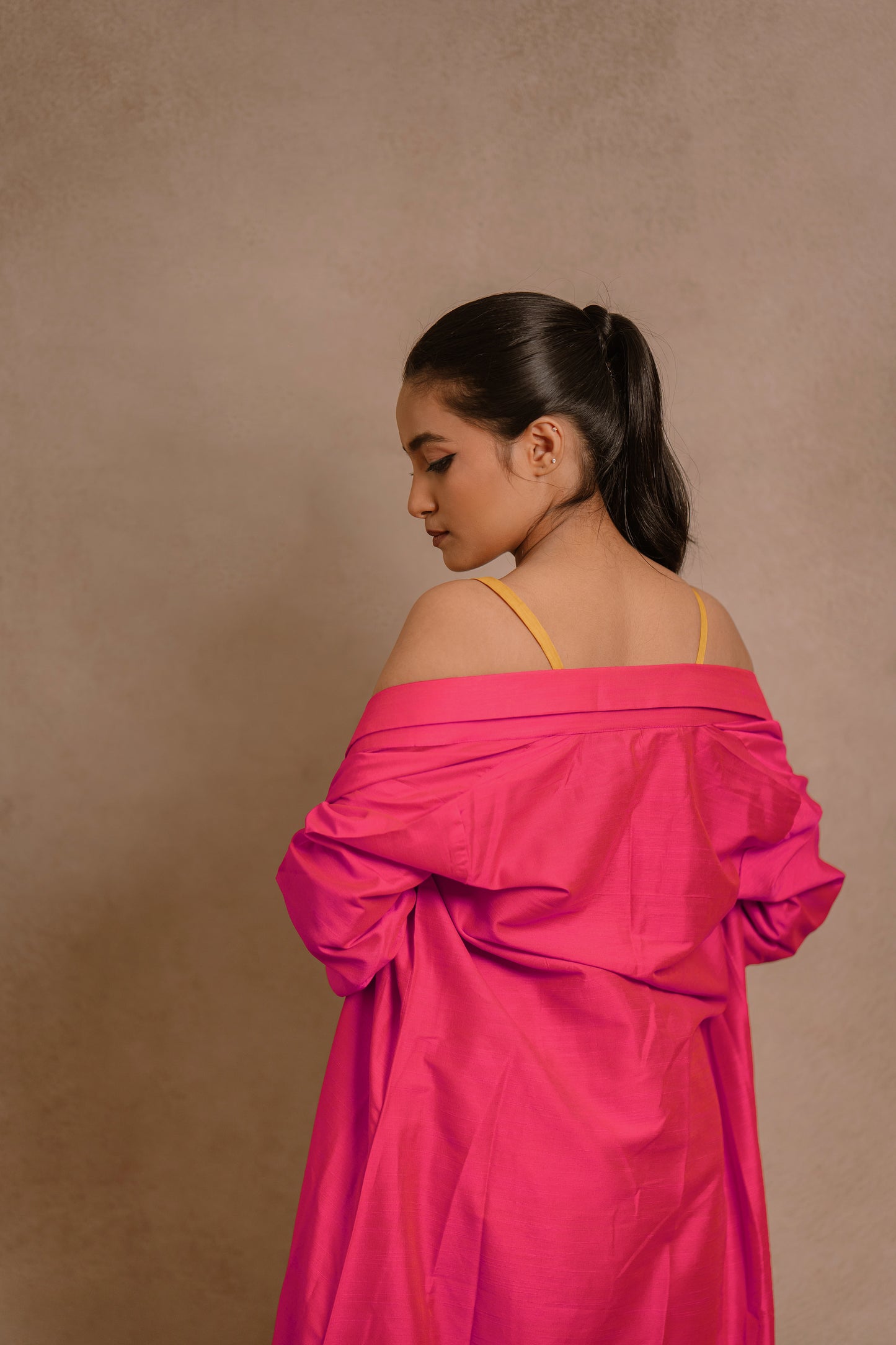 Model Krisha in a back closeup in a long jacket in hot pink paired with a crop top & bell bottom pant in yellow by team AKloset.
