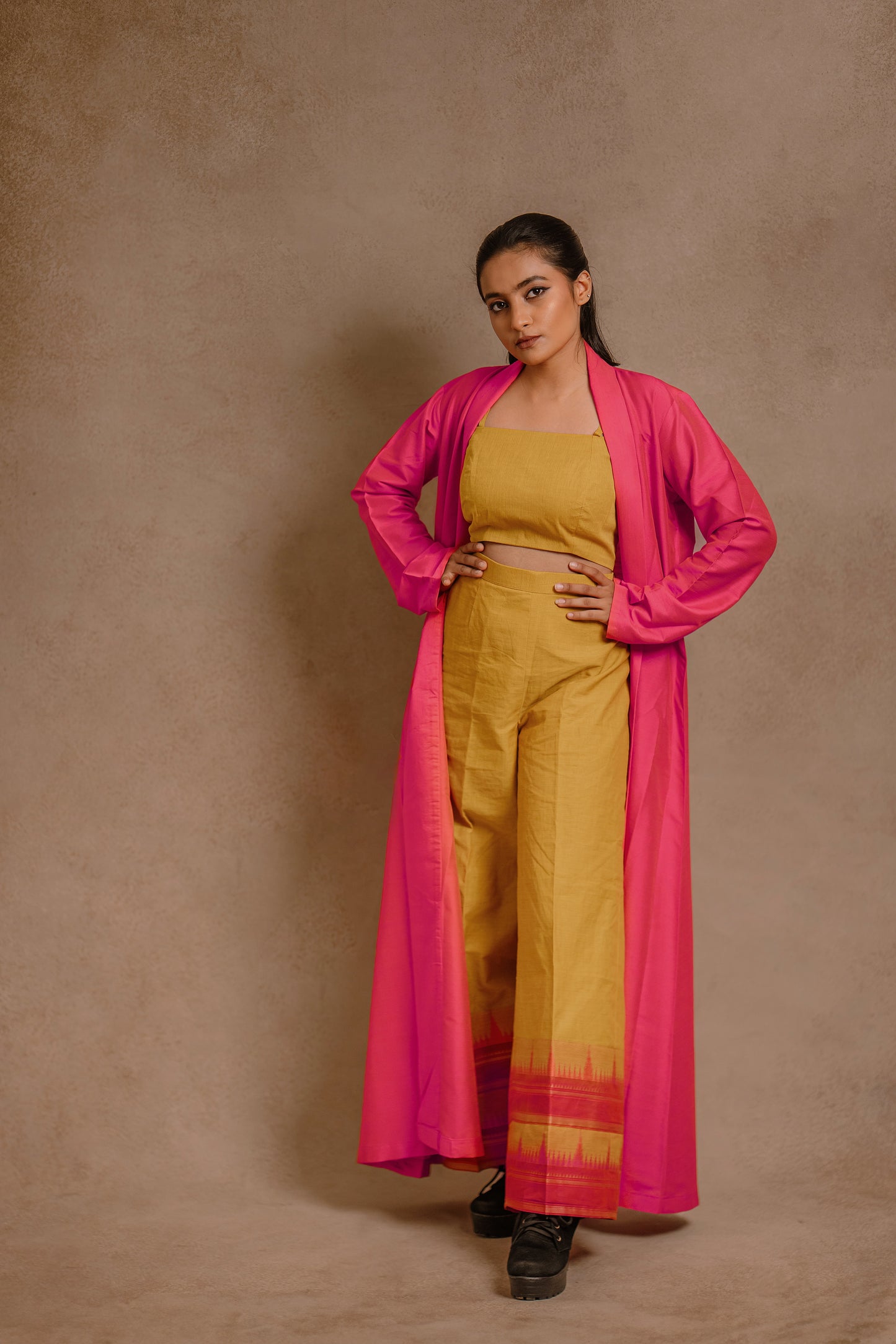Model Krisha in a long jacket in hot pink paired with a crop top & bell bottom pant in yellow by team AKloset.