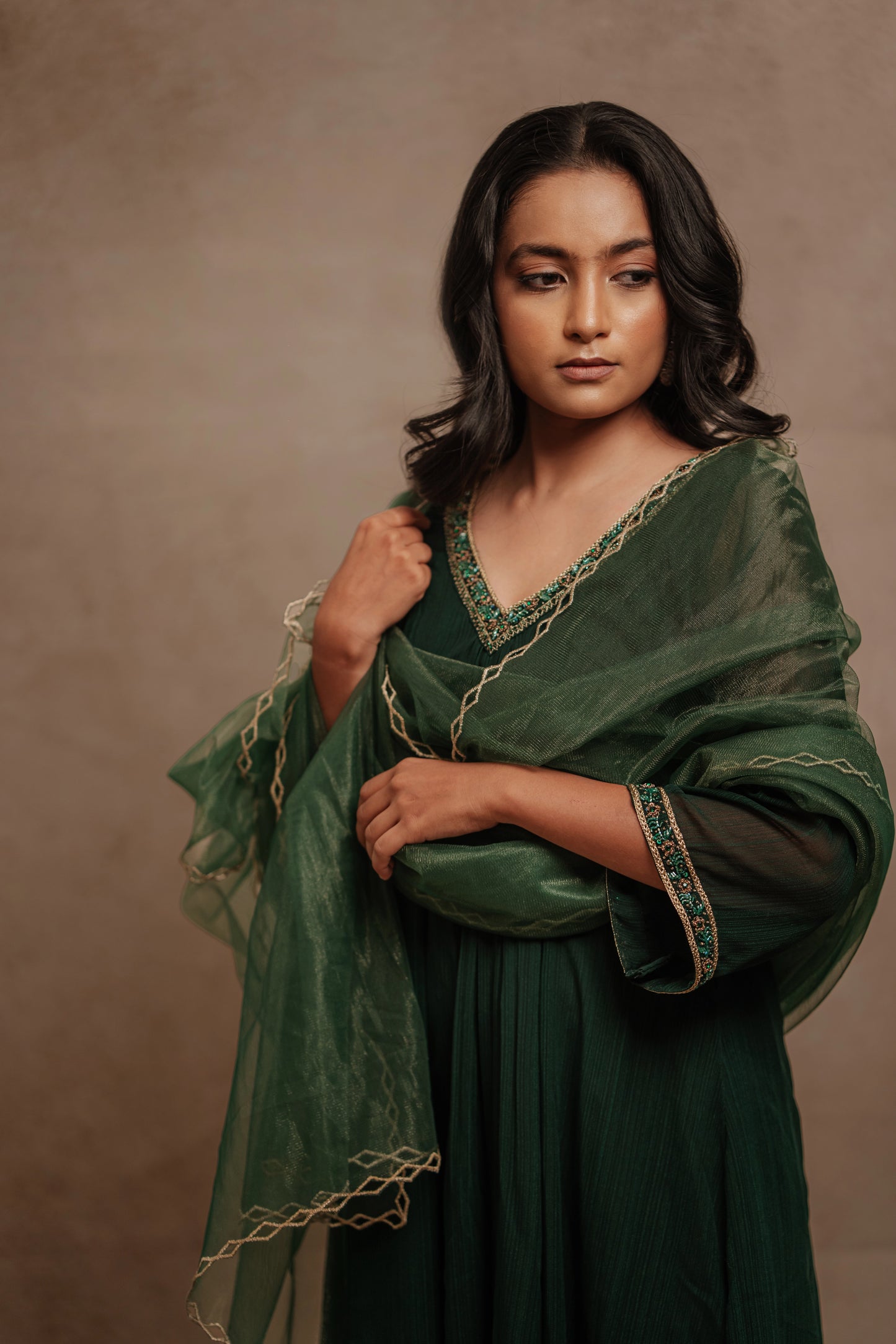 Model Krisha posing for closeup detailing in a hand embroidered tissue chiffon anarkali set in bottle green paired with a matching shimmer dupatta by team AKloset.