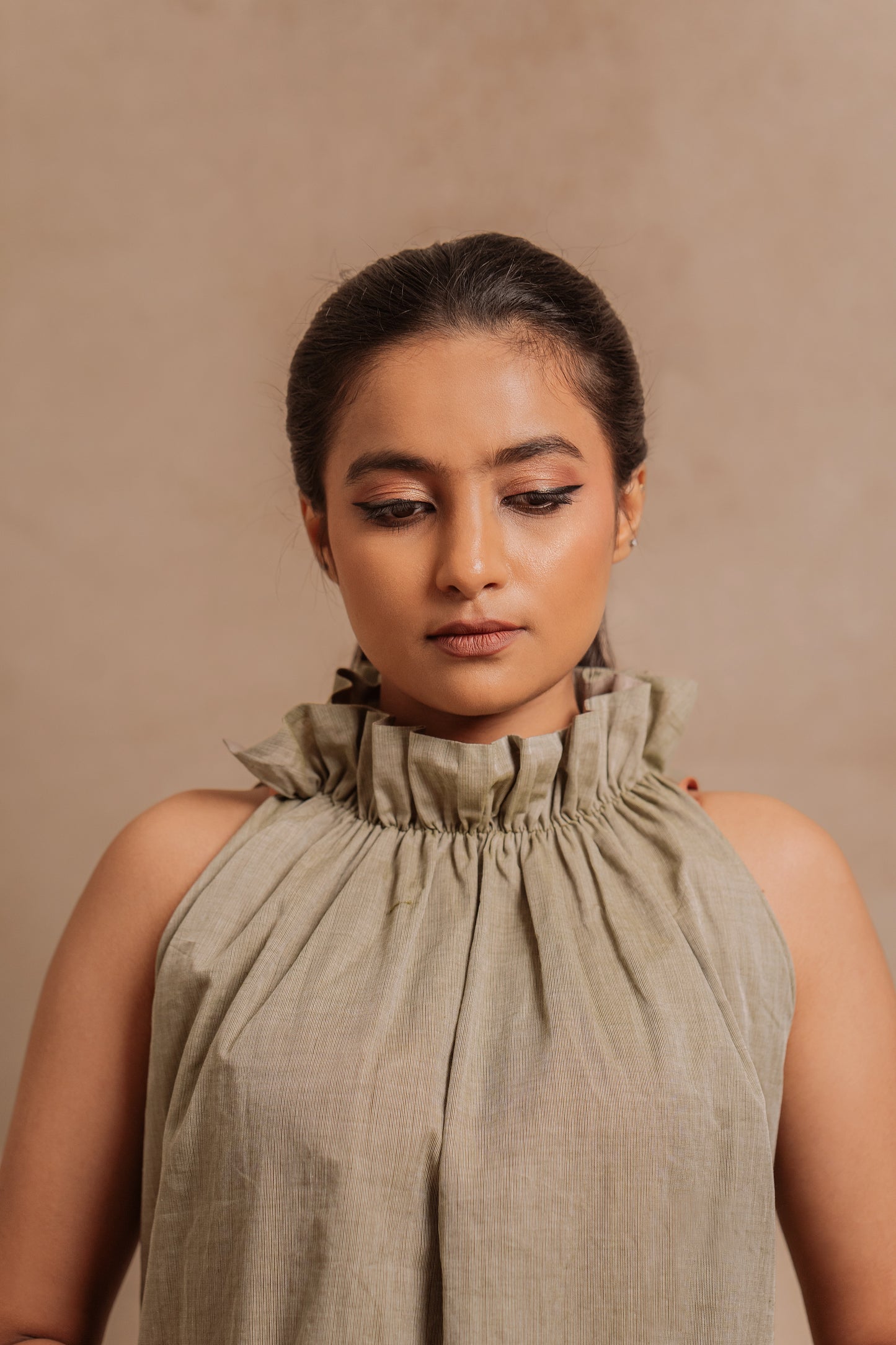 Model Krisha posing for closeup in a halterneck dress in sage green with a Halterneck by team Akloset.