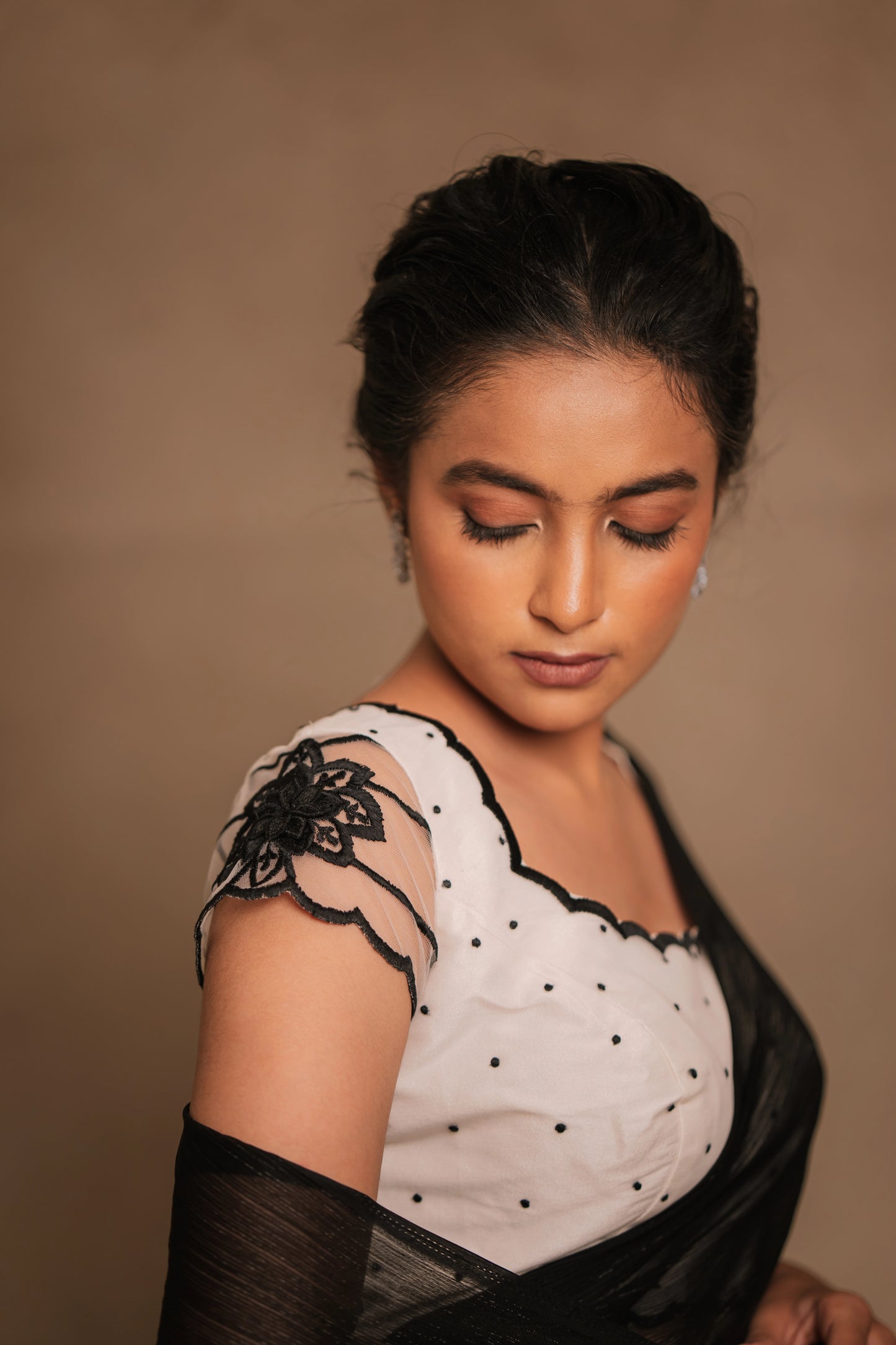 Model Krisha posing for photoshoot in an embroidered shimmer chiffon saree in black paired with a resham embroidered white tulle blouse by team AKloset.