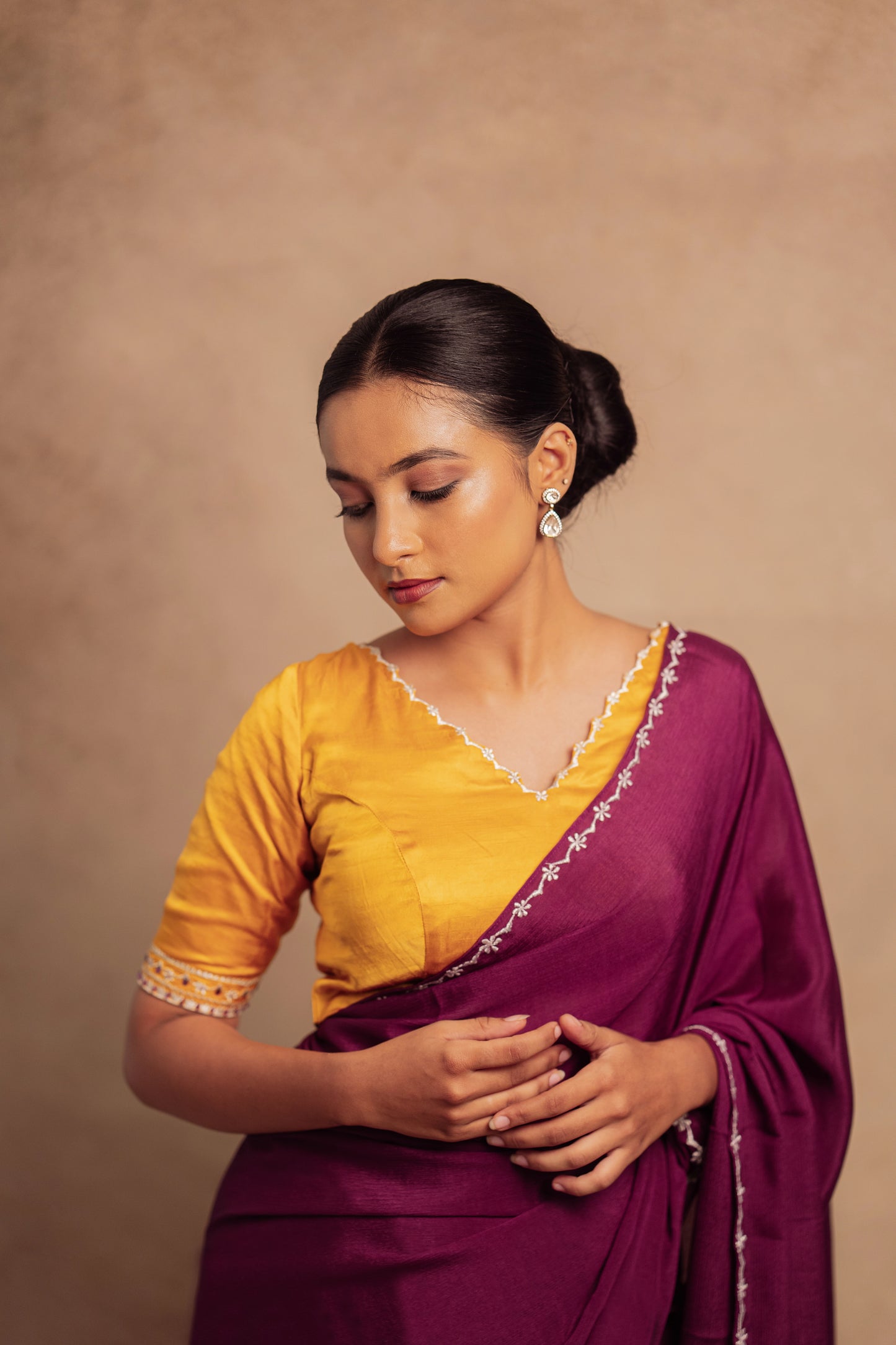 Model Krisha posing in a closeup in embroidered shimmer chiffon saree in purple paired with an embroidered mustard yellow chanderi blouse by AKloset.