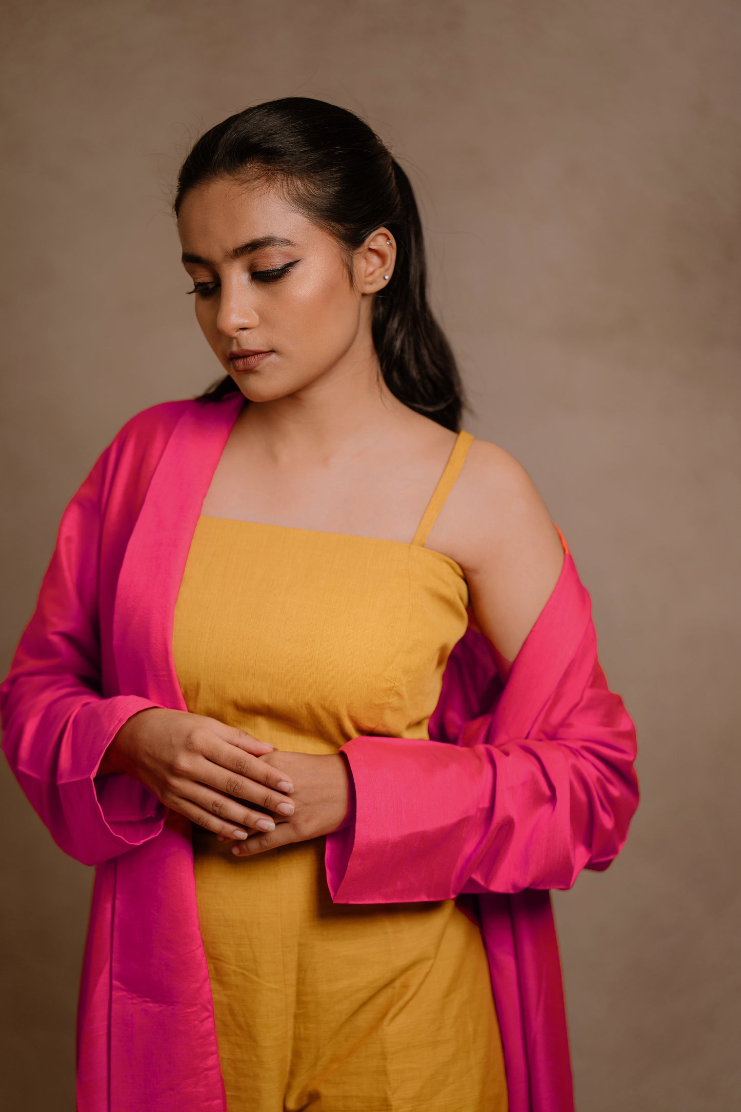 Model Krisha posing in a long jacket in hot pink paired with a crop top & bell bottom pant in yellow by team AKloset.