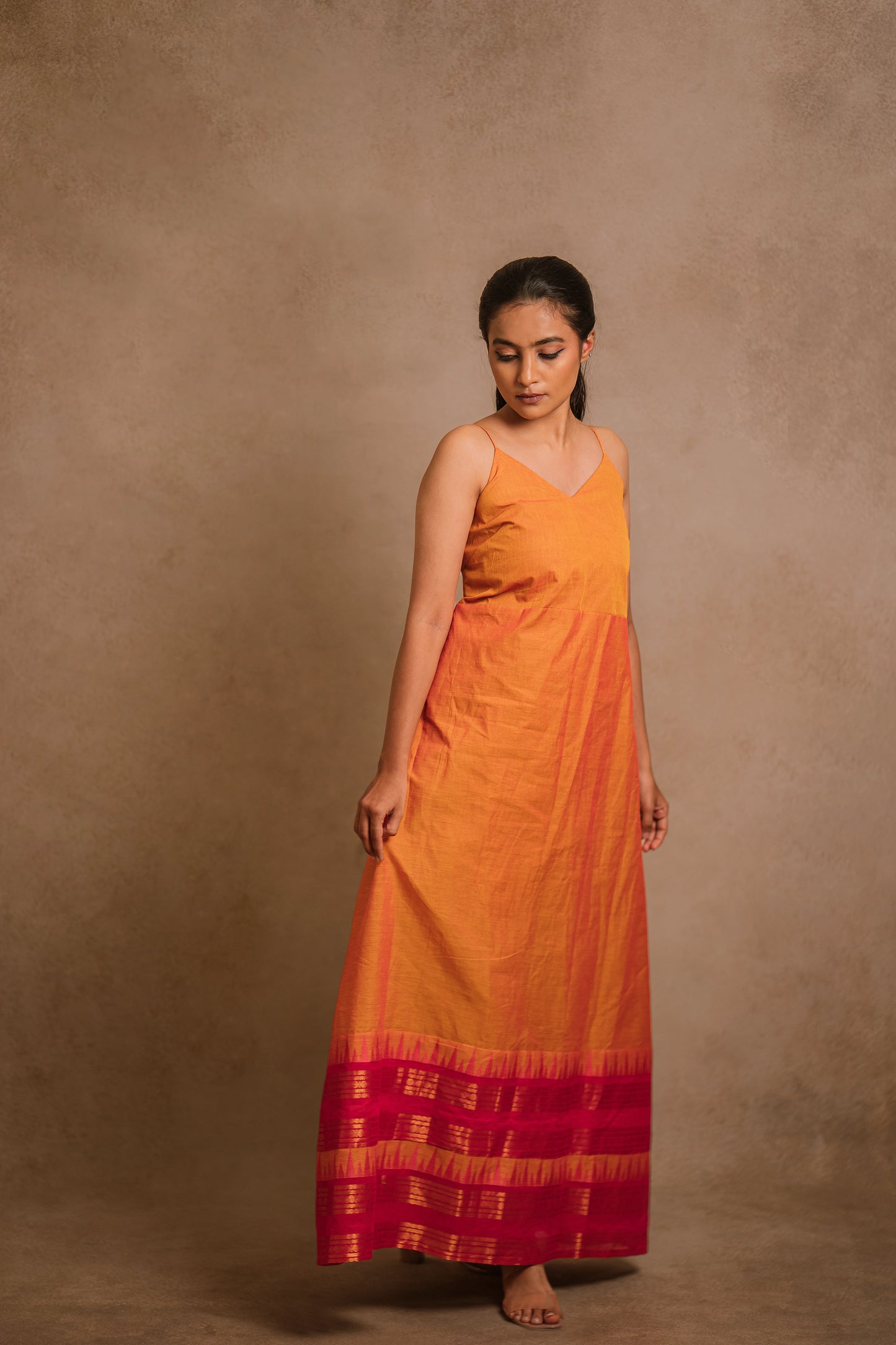 Model Krisha posing in an A-line sleeveless dress in orange (dual tone fabric) by team AKloset.