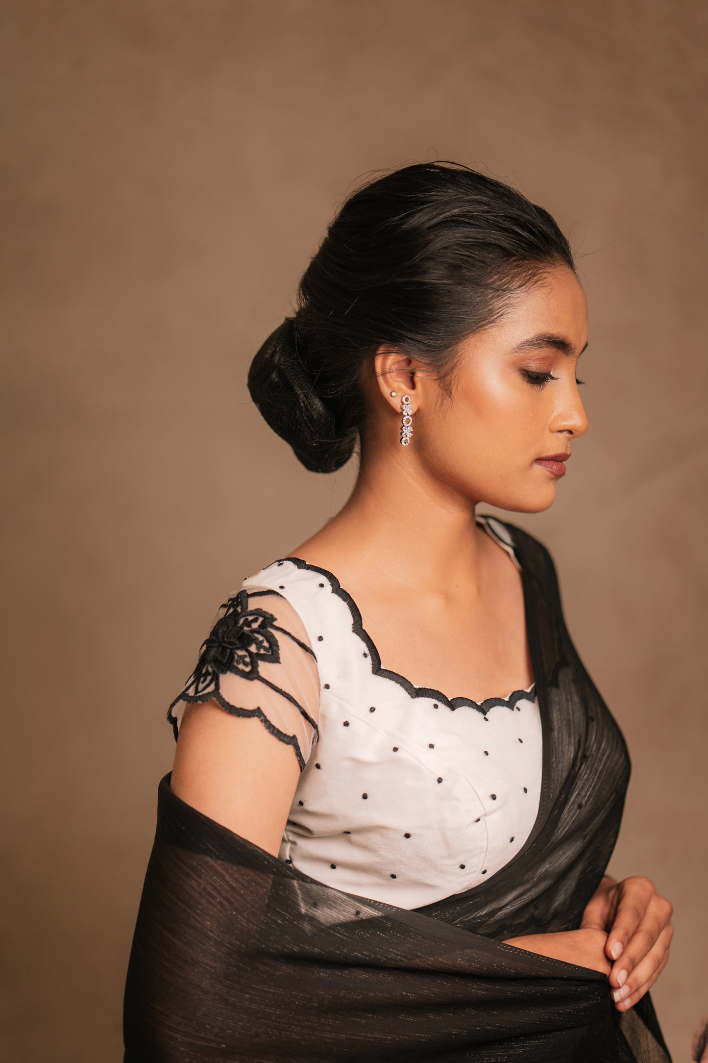 Model Krisha posing in an embroidered shimmer chiffon saree in black paired with a resham embroidered white tulle blouse by team AKloset.