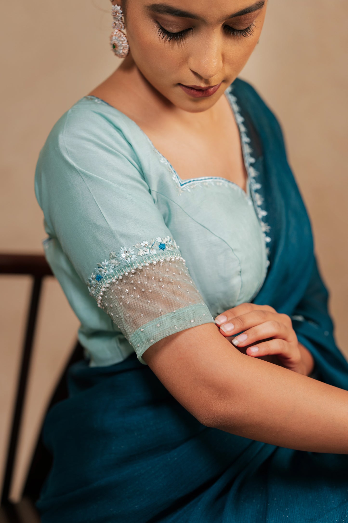 Model Krisha showcasing sleeves in embroidered shimmer chiffon saree in teal paired with a chanderi blouse in muted turquoise with pearl beads detailing by team AKloset.