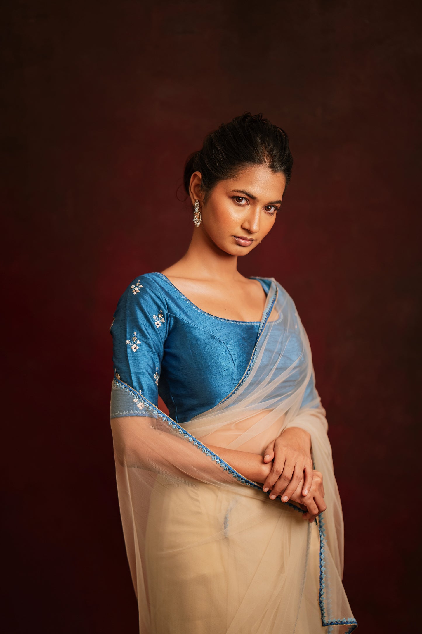 Model Premika Sekar posing during photoshoot in an ivory tulle saree embroidered with resham paired with an embroidered rawsilk blouse in cerulean blue by team AKloset.