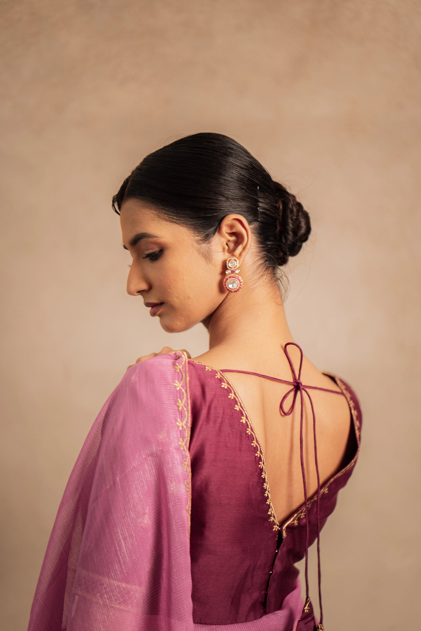 Model Premika Sekar posing for back blouse design in an embroidered Tissue Chiffon Saree in Onion Pink with an Embroidered Chanderi Blouse in Plum.