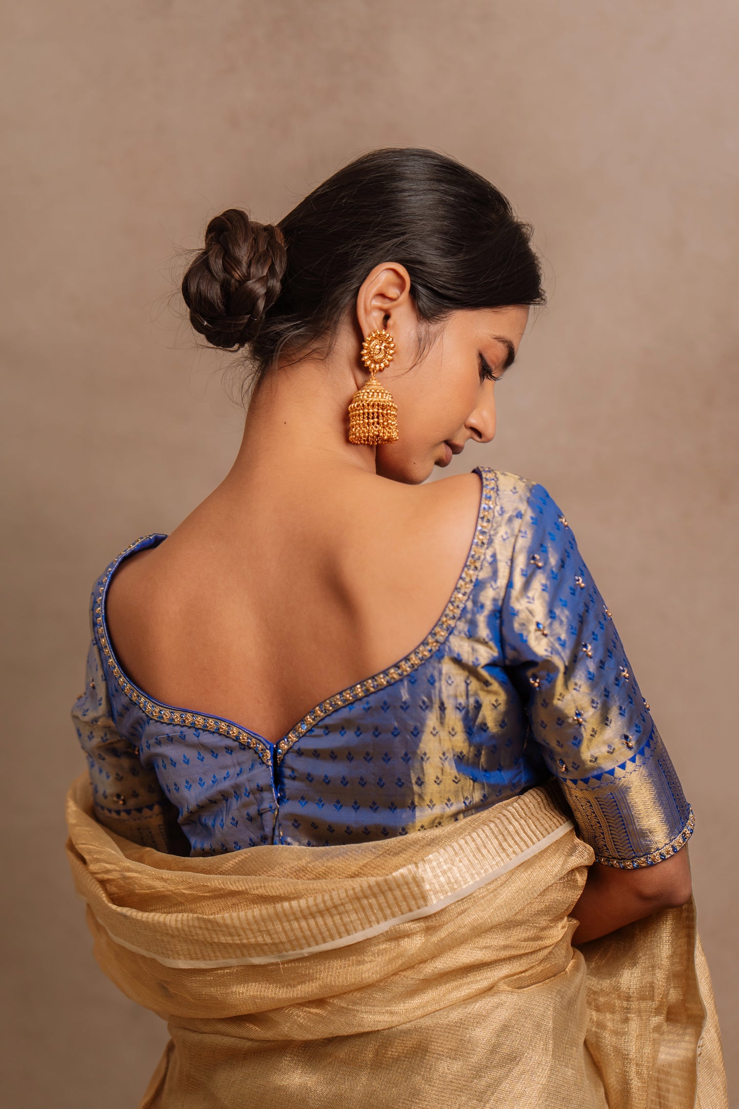 Model Premika Sekar posing for back detailing in a hand embroidered Kanjivaram tissue silk blouse in blue (Dual Tone Silk) by team AKloset.