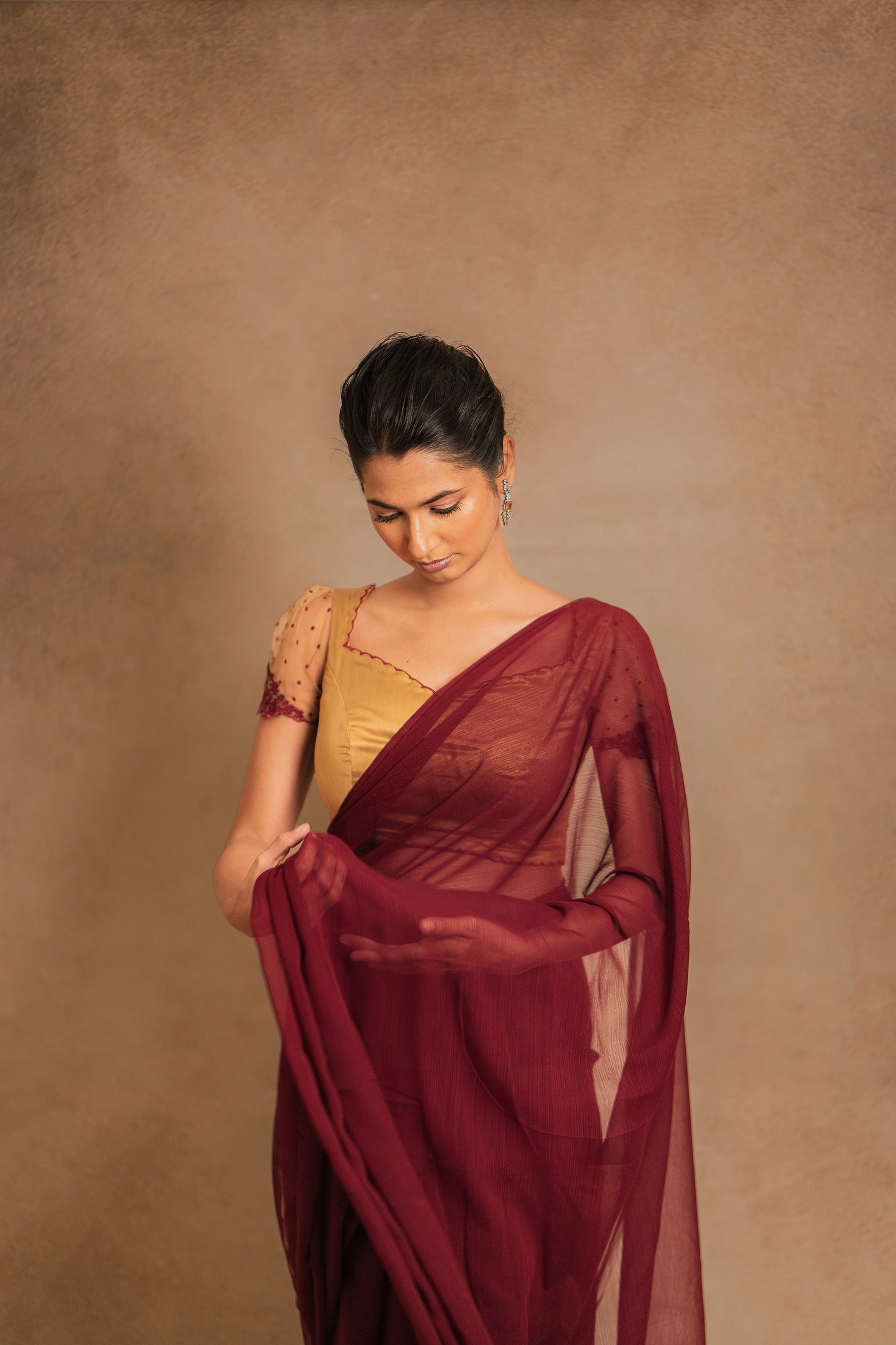 Model Premika Sekar posing for front profile in a saree in maroon tulle embroidered with resham paired with an embroidered satin blouse in light brown by team AKloset.