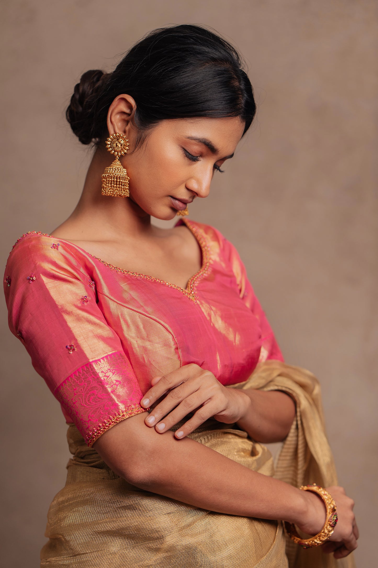 Model Premika Sekar showcasing sleeve detailing in a hand embroidered Kanjivaram tissue silk blouse in pink (Dual Tone Silk) by team AKloset.
