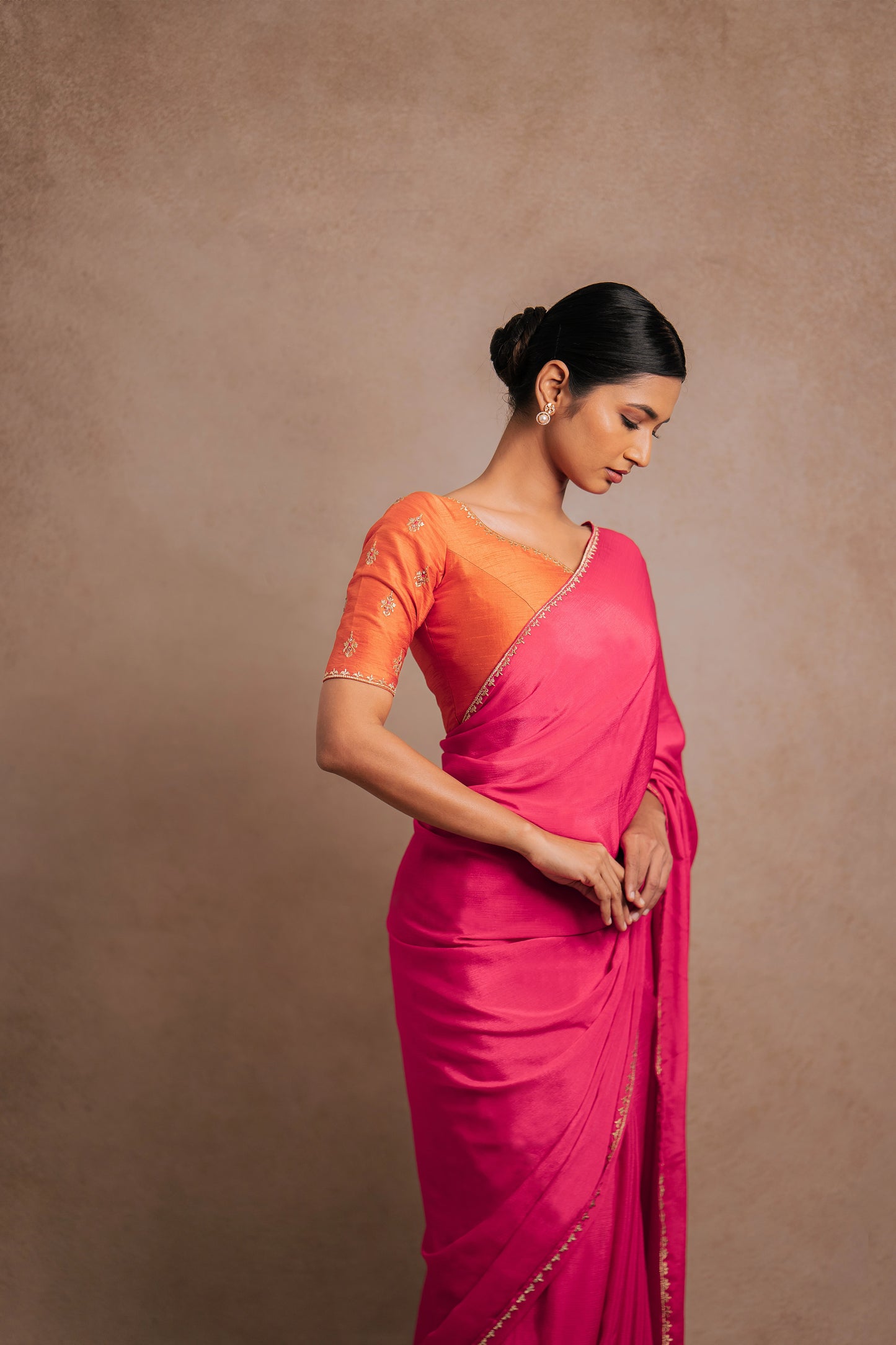 Model Premika Sekar posing for photoshoot in a pink shimmer chiffon saree paired with an embroidered orange raw silk blouse designed by team AKloset.