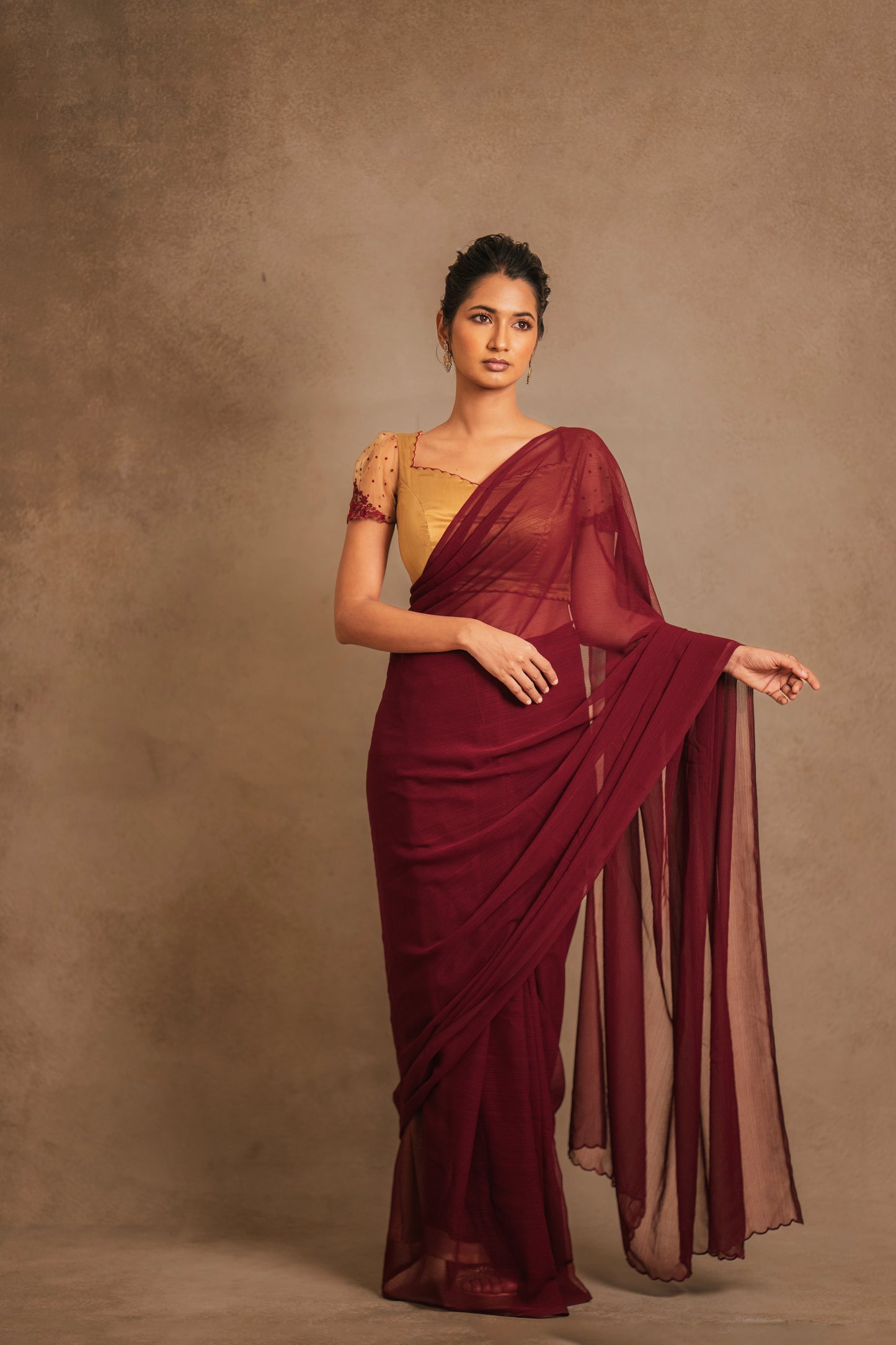Model Premika Sekar posing for photoshoot in a saree in maroon tulle embroidered with resham paired with an embroidered satin blouse in light brown by team AKloset.