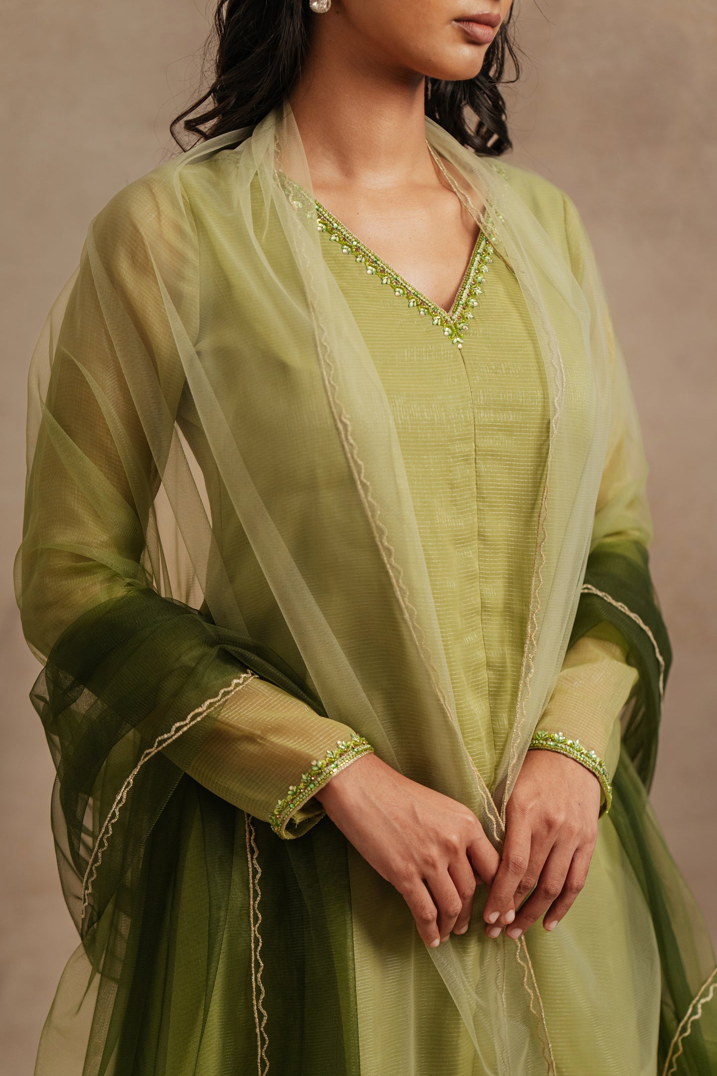 Model Premika Sekar posing for photoshoot in an embroidered tissue chiffon salwar set in sage green, paired with a tulle dupatta in ombré by team AKloset.