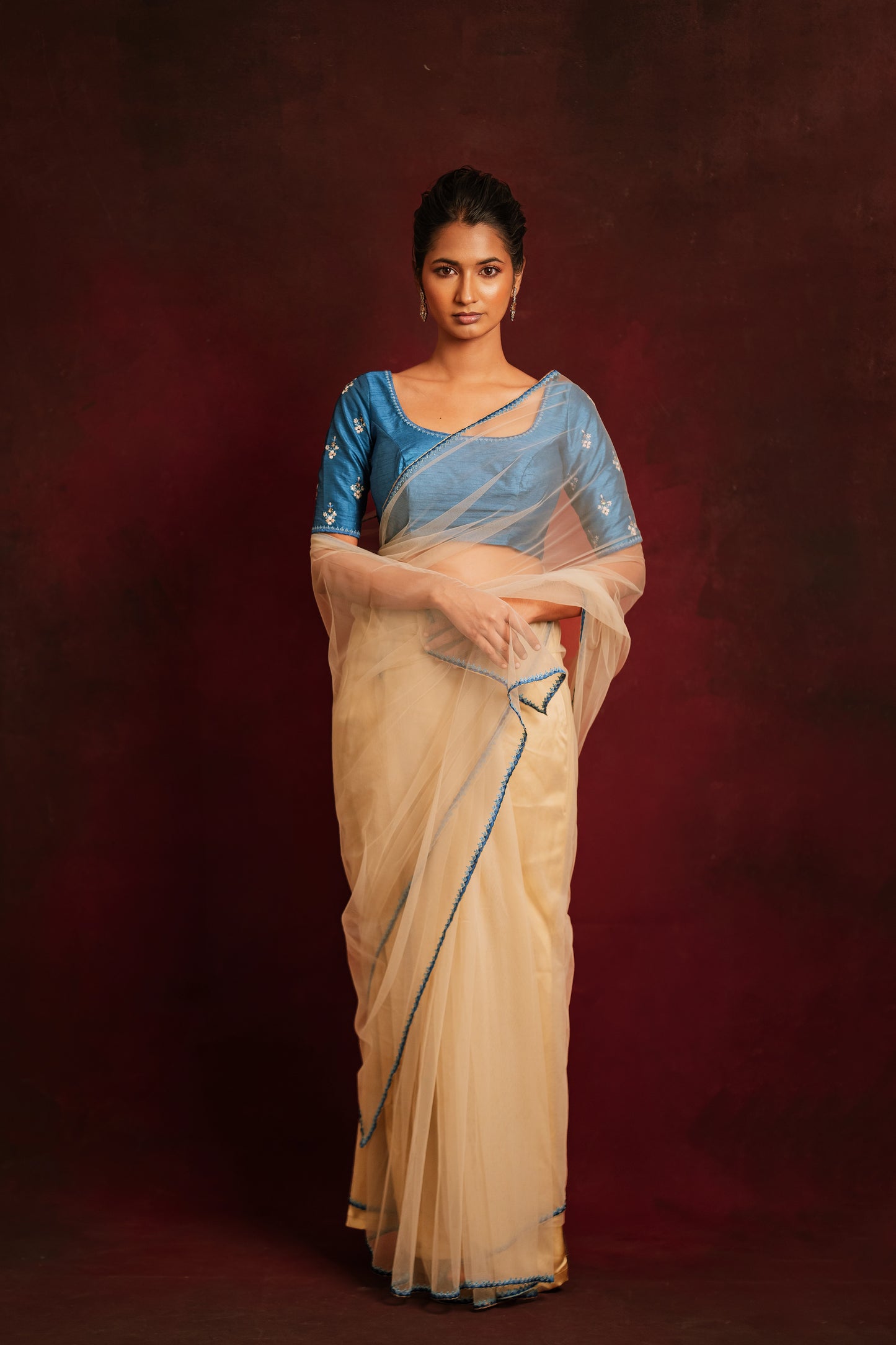Model Premika Sekar posing for photoshoot in an ivory tulle saree embroidered with resham paired with an embroidered rawsilk blouse in cerulean blue by team AKloset.
