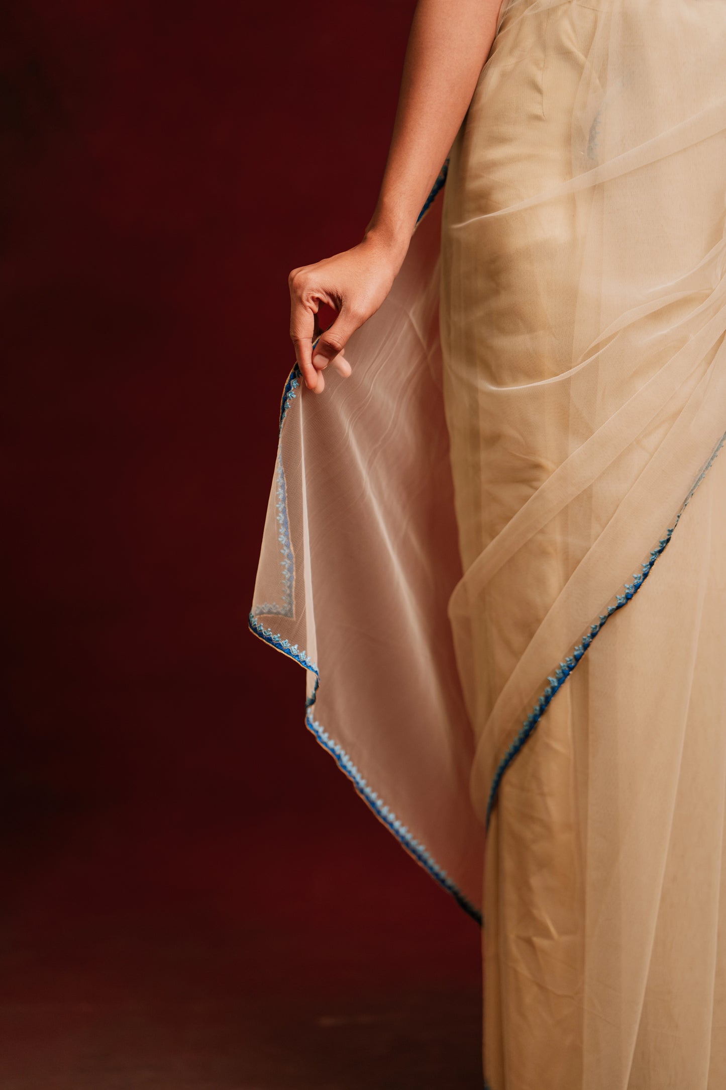 Model Premika Sekar posing for saree detailing in an ivory tulle saree embroidered with resham paired with an embroidered rawsilk blouse in cerulean blue by team AKloset.