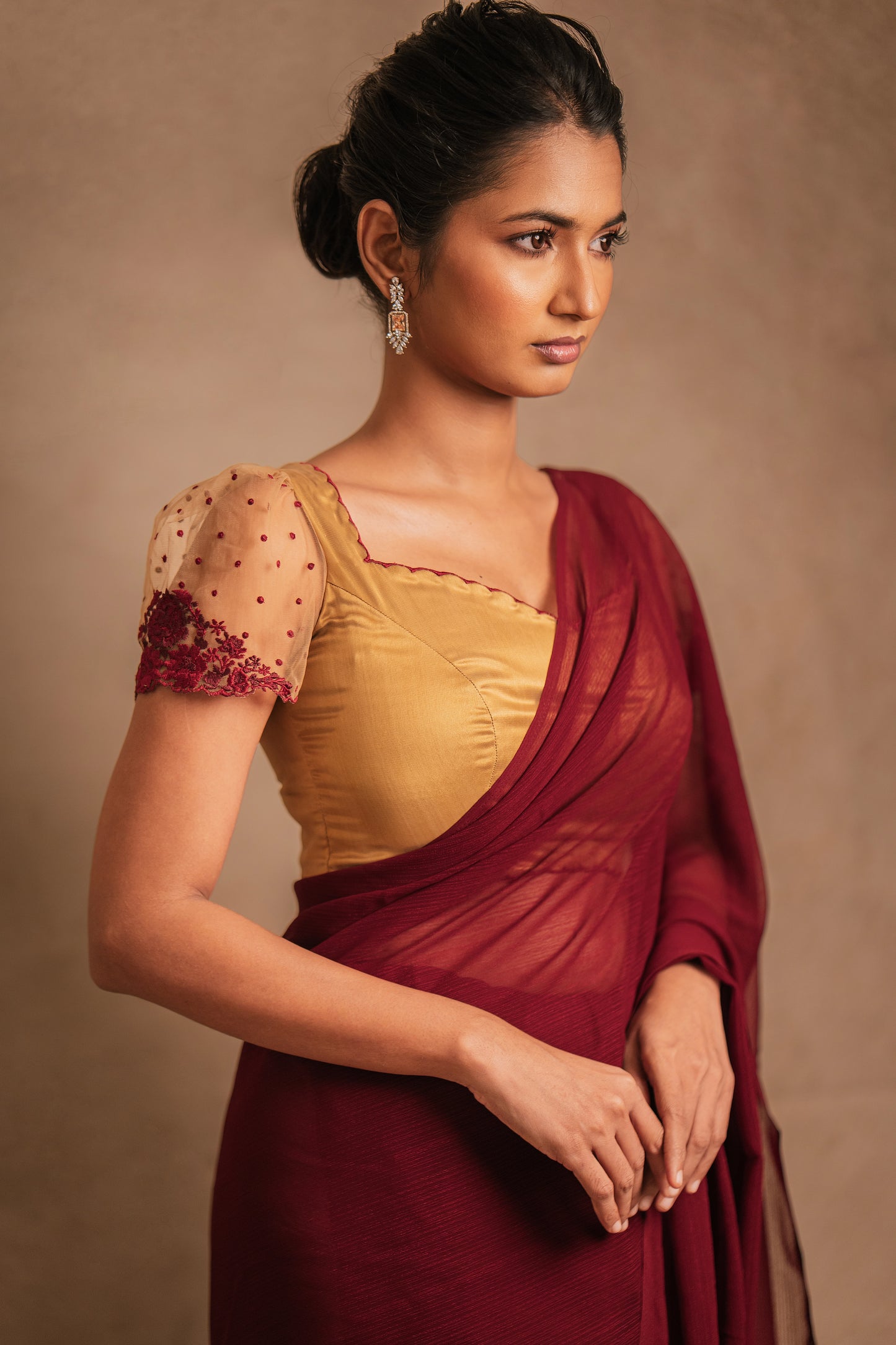 Model Premika Sekar posing for sleeve detailing in a saree in maroon tulle embroidered with resham paired with an embroidered satin blouse in light brown by team AKloset.
