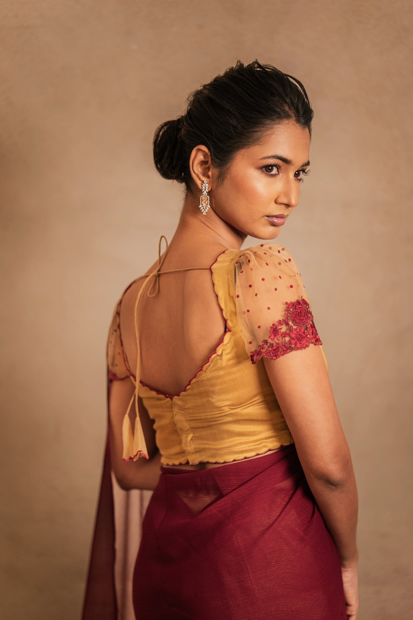 Model Premika Sekar posing in a saree in maroon tulle embroidered with resham paired with an embroidered satin blouse in light brown by team AKloset.