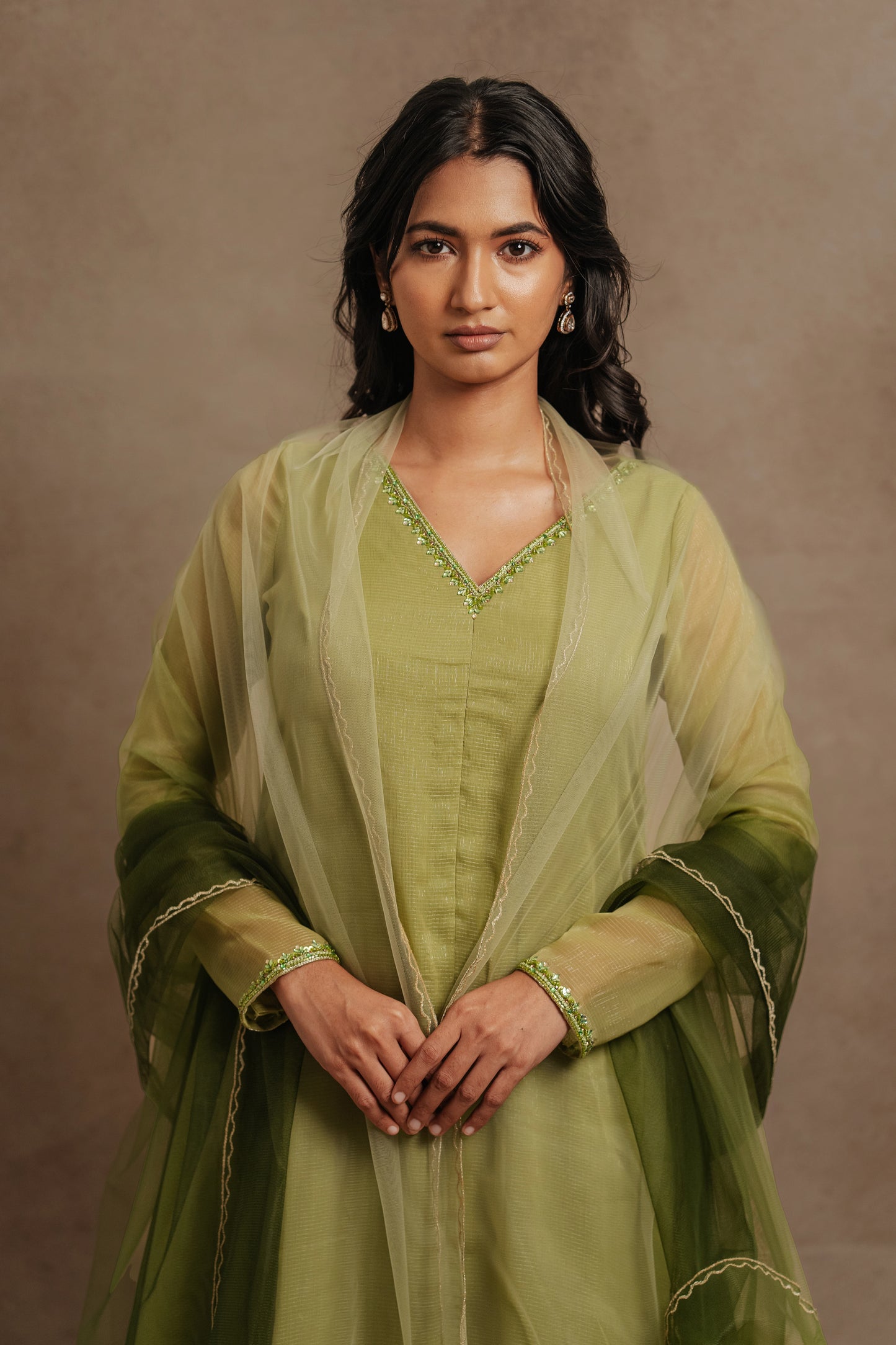 Model Premika Sekar posing in an embroidered tissue chiffon salwar set in sage green, paired with a tulle dupatta in ombré by team AKloset.
