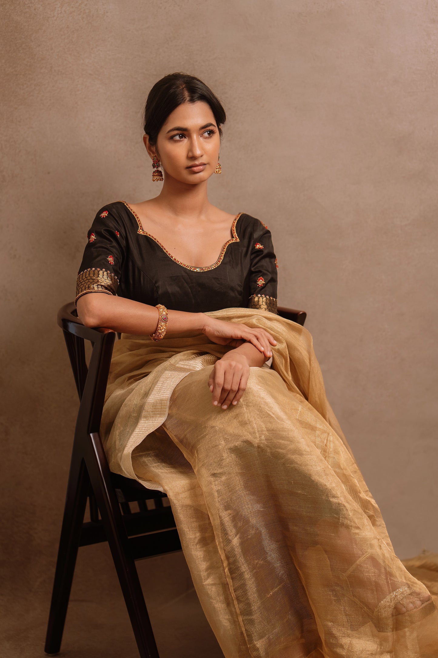 Model Premika Sekar posing seated in a hand embroidered kanjivaram silk blouse in black by team AKloset.