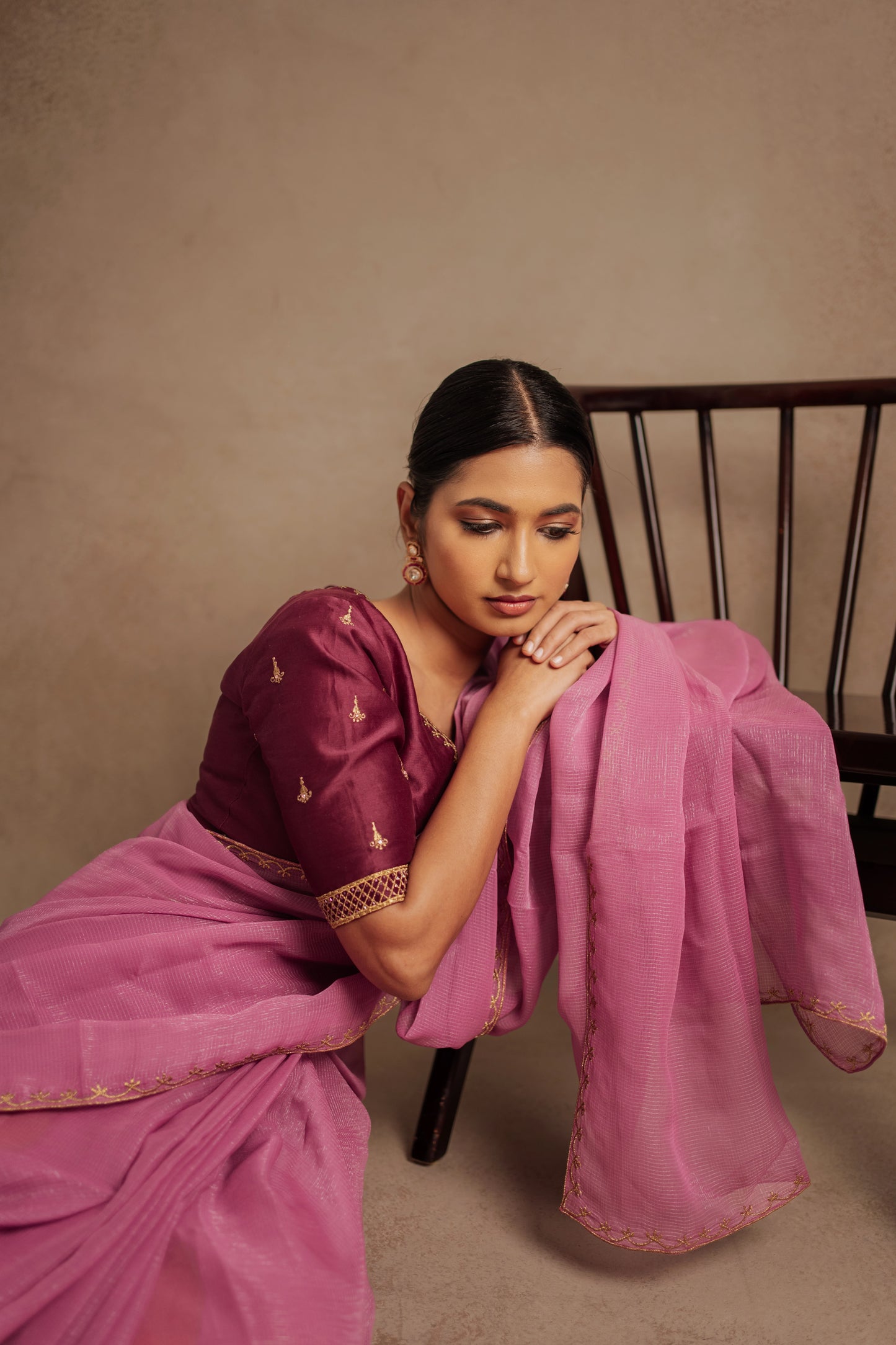 Model Premika Sekar posing seated in an embroidered Tissue Chiffon Saree in Onion Pink with an Embroidered Chanderi Blouse in Plum.