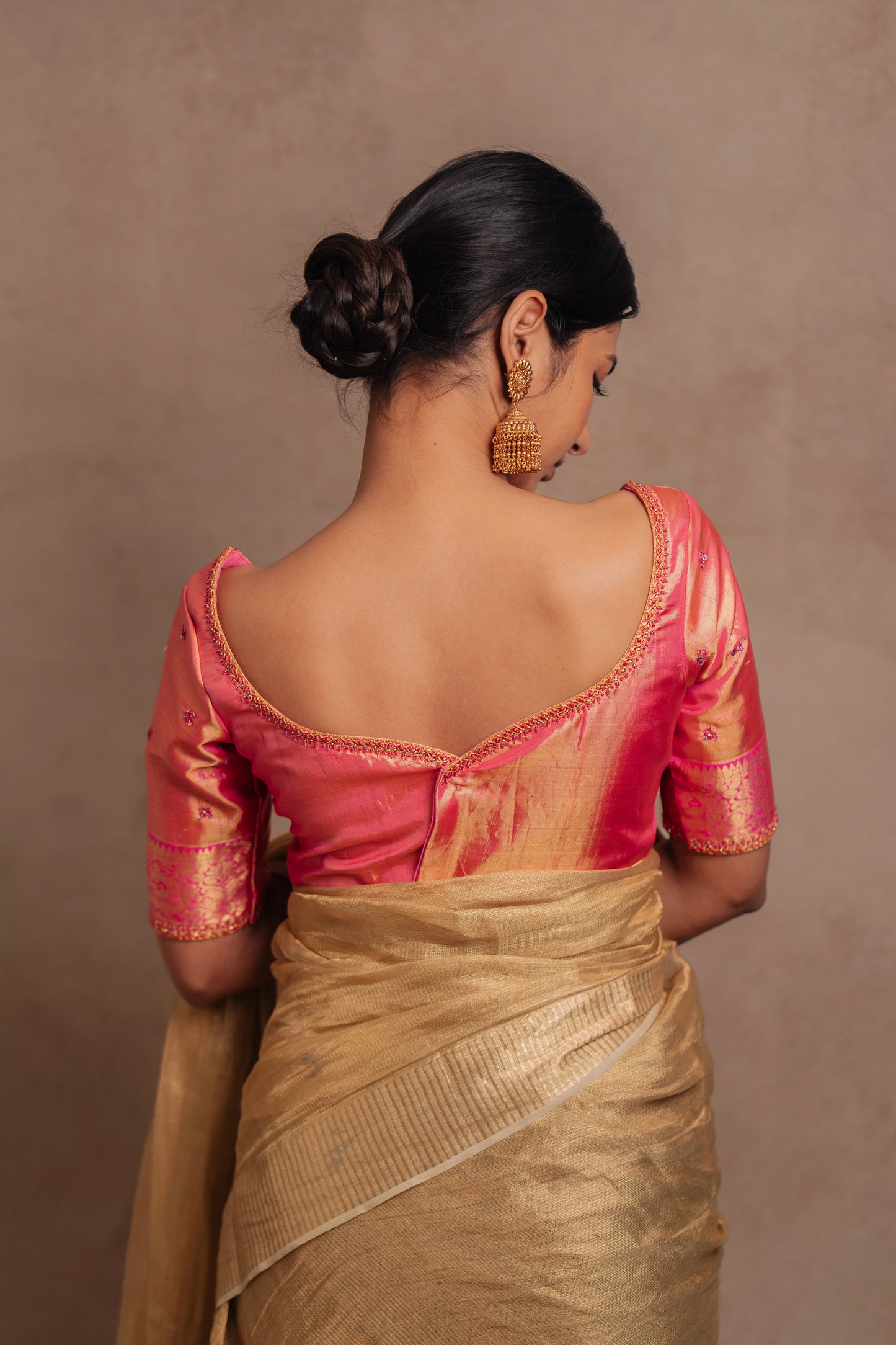 Model Premika Sekar showcasing back detailing in a hand embroidered Kanjivaram tissue silk blouse in pink (Dual Tone Silk) by team AKloset.